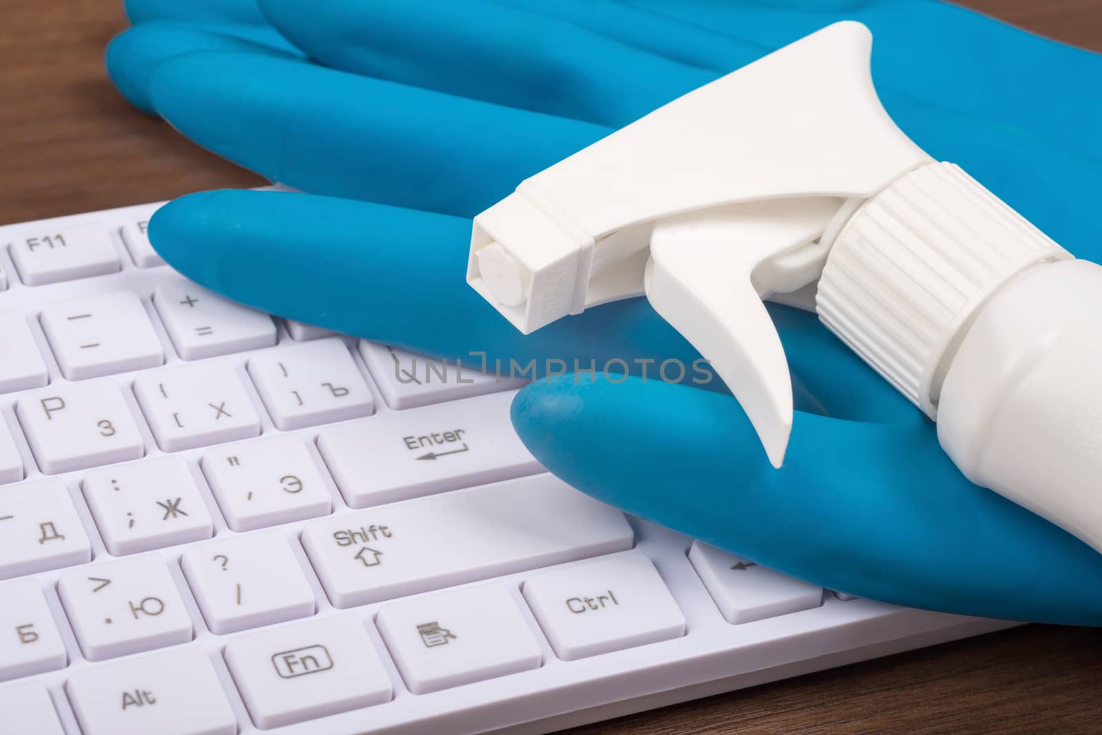 Airbrush with rubber gloves and keyboard on brown wooden table, side view