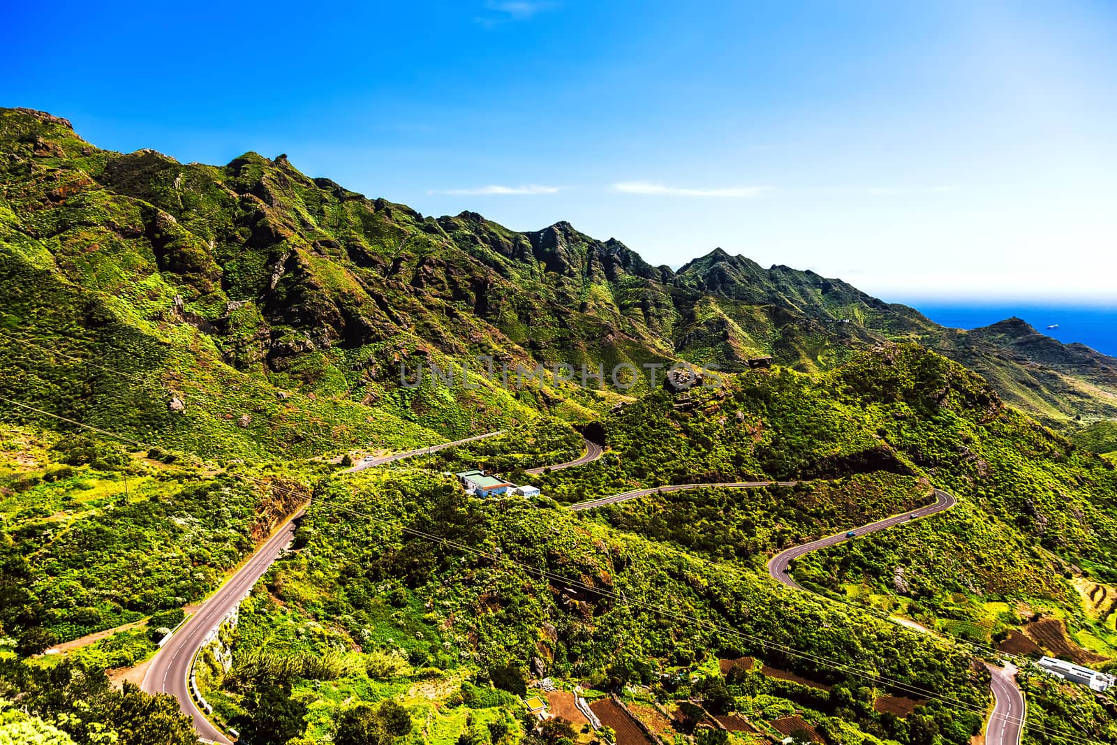 Green mountains or rocks valley with winding road and sky with ocean on horizon landscape in Tenerife Canary island, Spain at summer