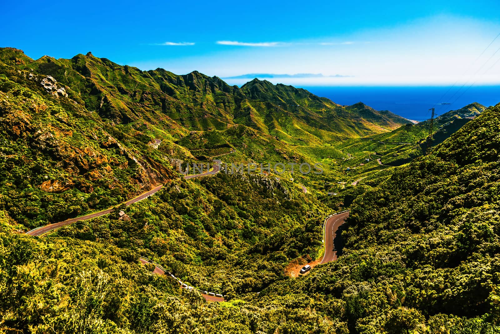 Green mountains or rocks valley with winding or serpantine road and sky with ocean on skyline landscape in Tenerife Canary island, Spain at spring