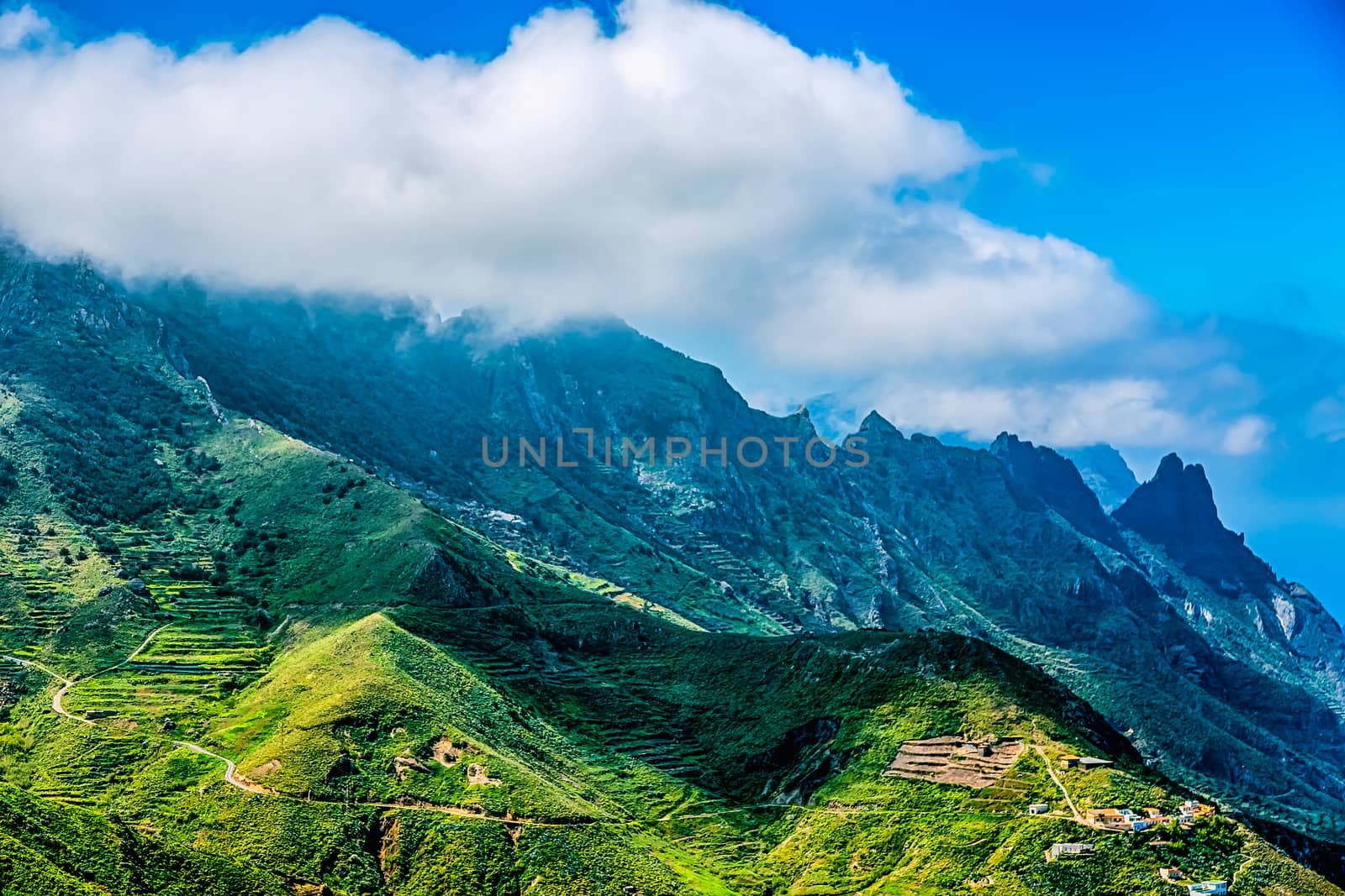 Green mountains or rock with clouds over peak and blue sky