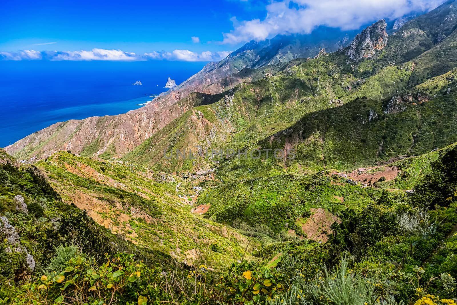 Green mountains or rocks with clouds over peak and  sky horizon near the Atlantic ocean landscape in Tenerife Canary island, Spain