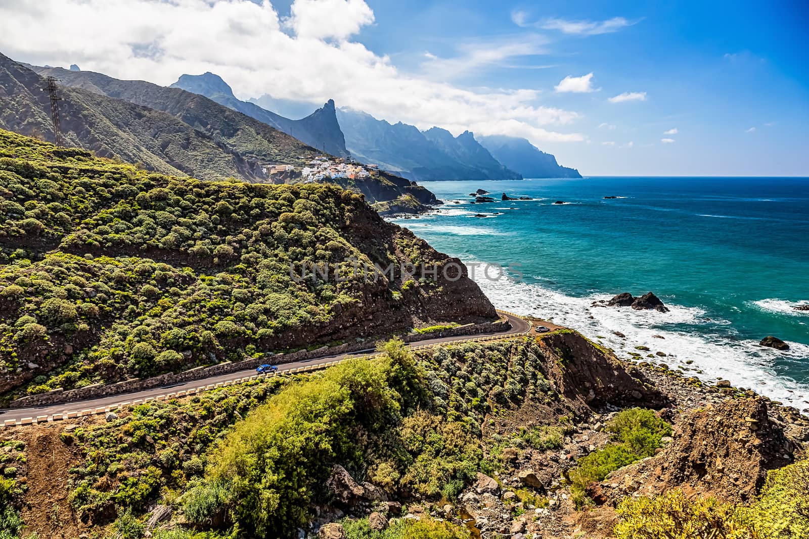 Road near coast of Atlantic ocean with mountains or rocks and blue sky with clouds and skyline or horizon in Tenerife Canary island, Spain at spring or summer