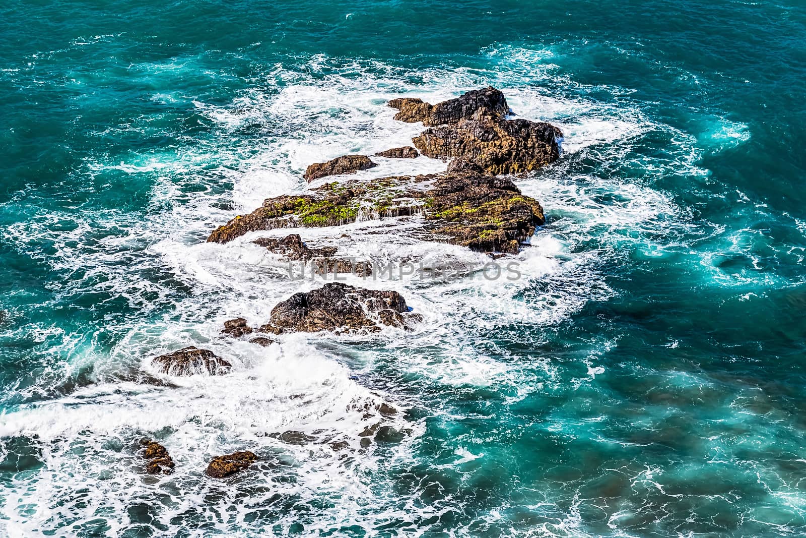 Stones in waves of ocean on shore of Atlantic ocean in Tenerife Canary island, Spain at spring or summer