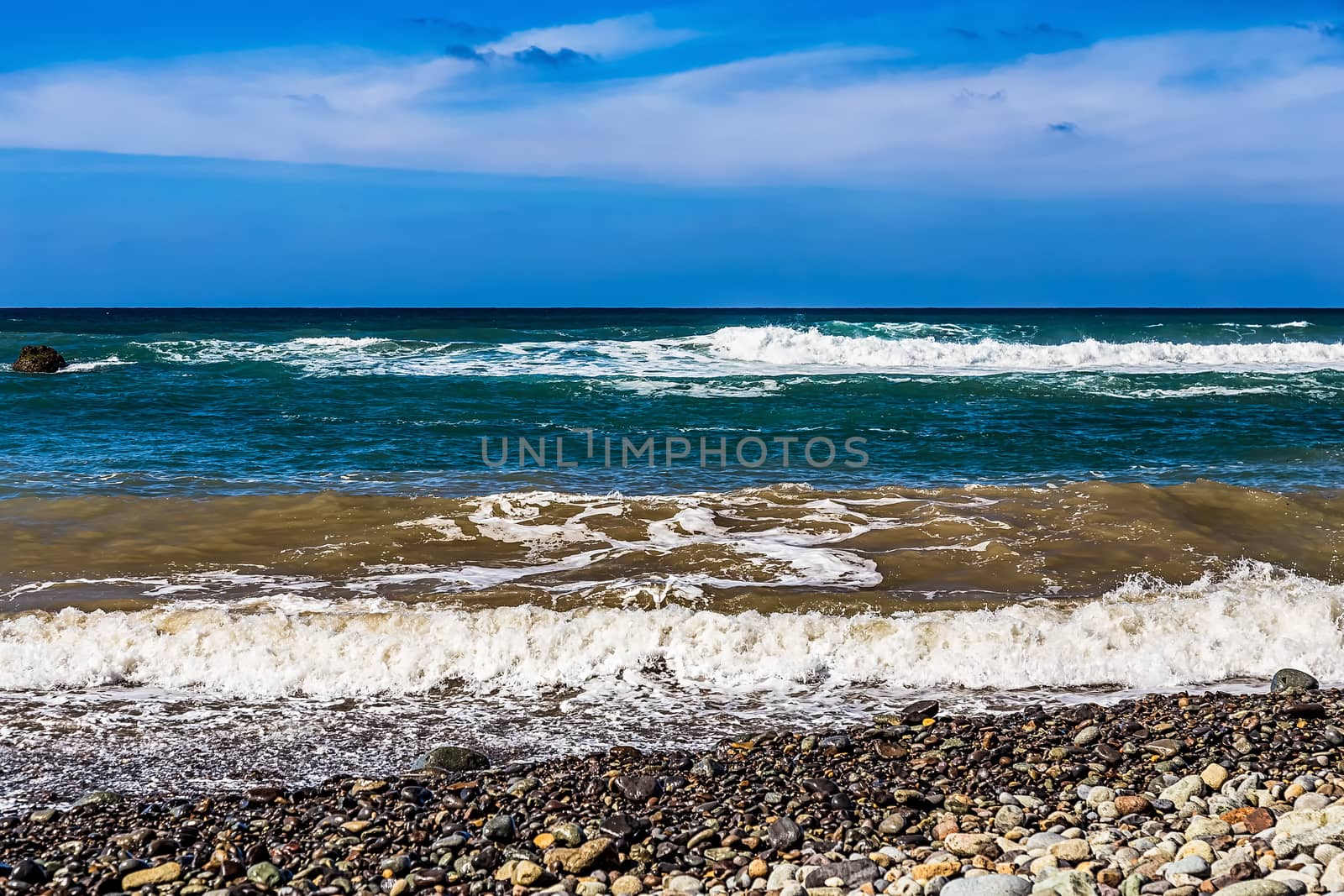 Wild stone beach on coast or shore of the Atlantic ocean with waves and sky with clouds and skyline or horizon in Tenerife Canary island, Spain at spring or summer