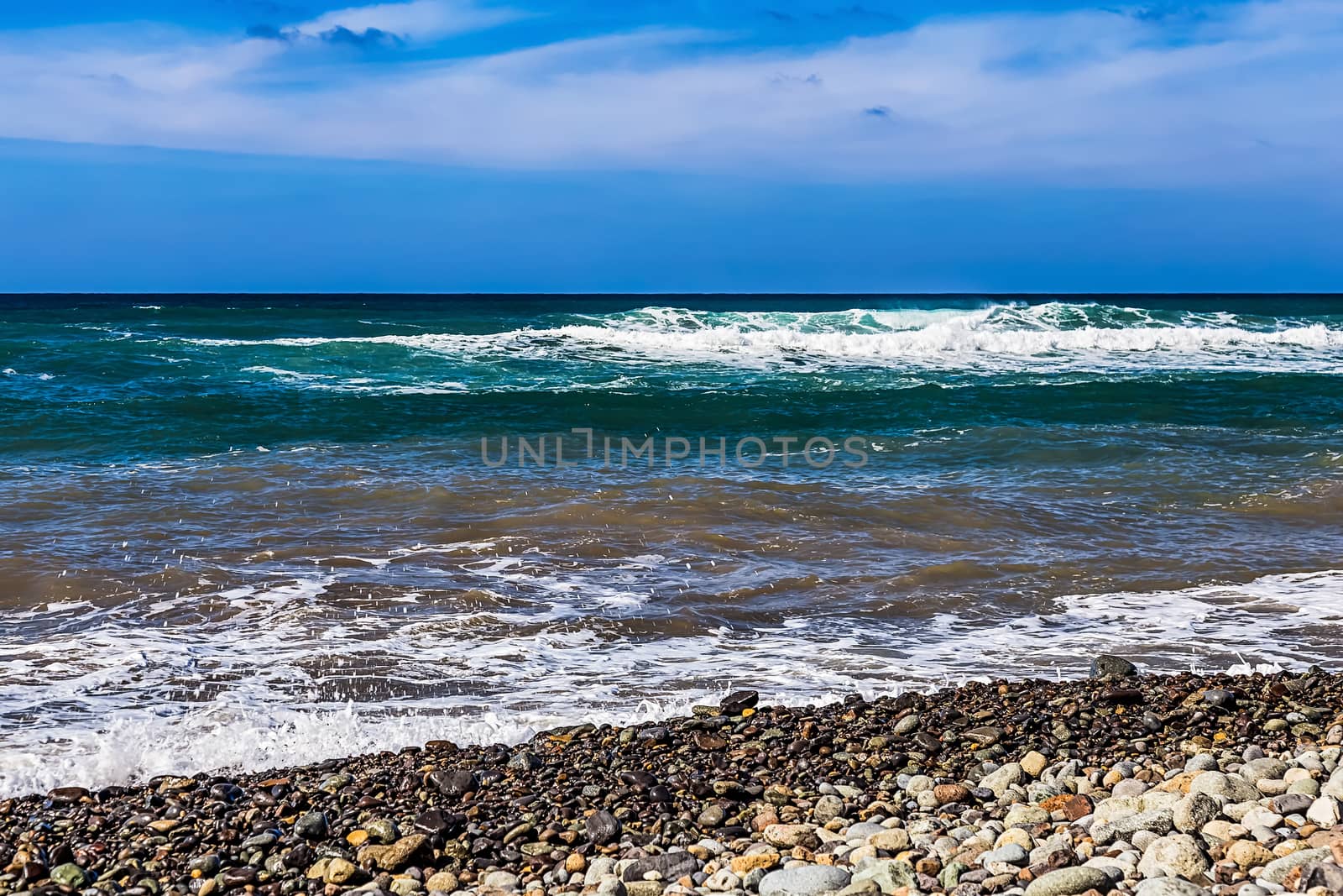 Wild stone beach on coast or shore of the Atlantic ocean with waves and sky with clouds and skyline or horizon in Tenerife Canary island, Spain