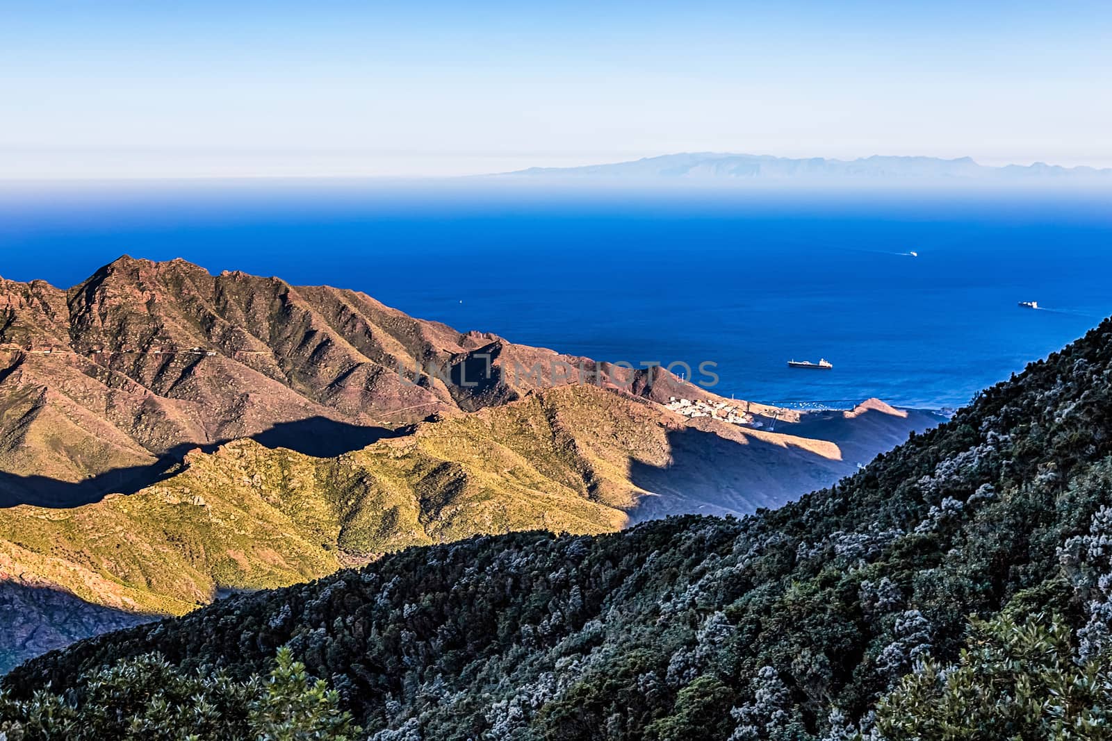 Coast of Atlantic ocean with green mountain or rock and blue sky with horizon in Tenerife Canary island, Spain at spring or summer