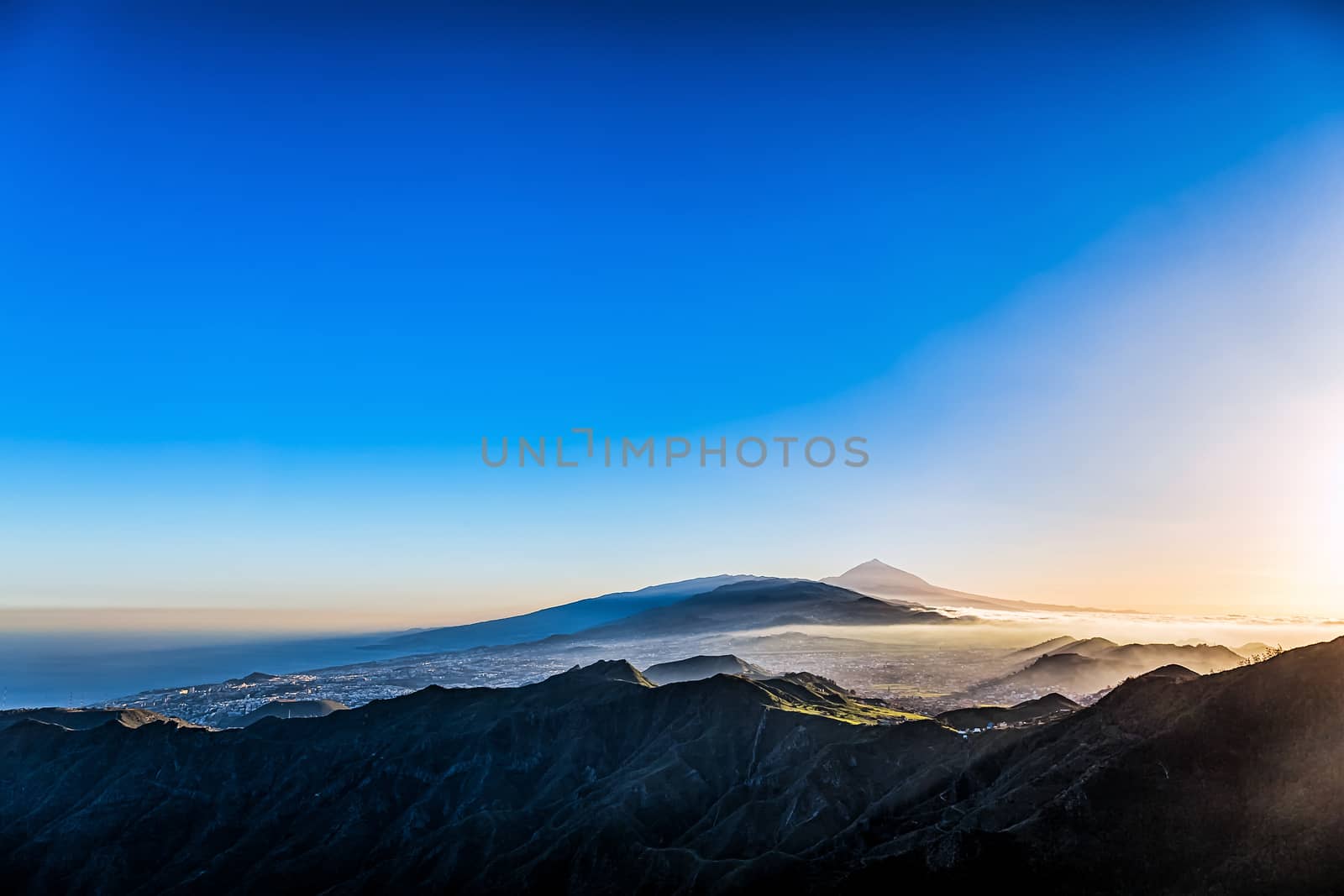 Sunset at evening in mountains and blue sky with haze and Teide volcano on background in Tenerife Canary island, Spain at spring or summer