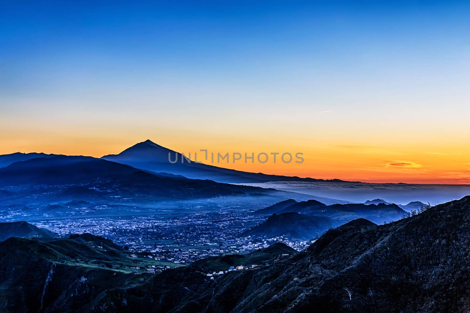 Evening sunset in mountains and blue sky with fog or haze and Teide volcano on background in Tenerife Canary island, Spain