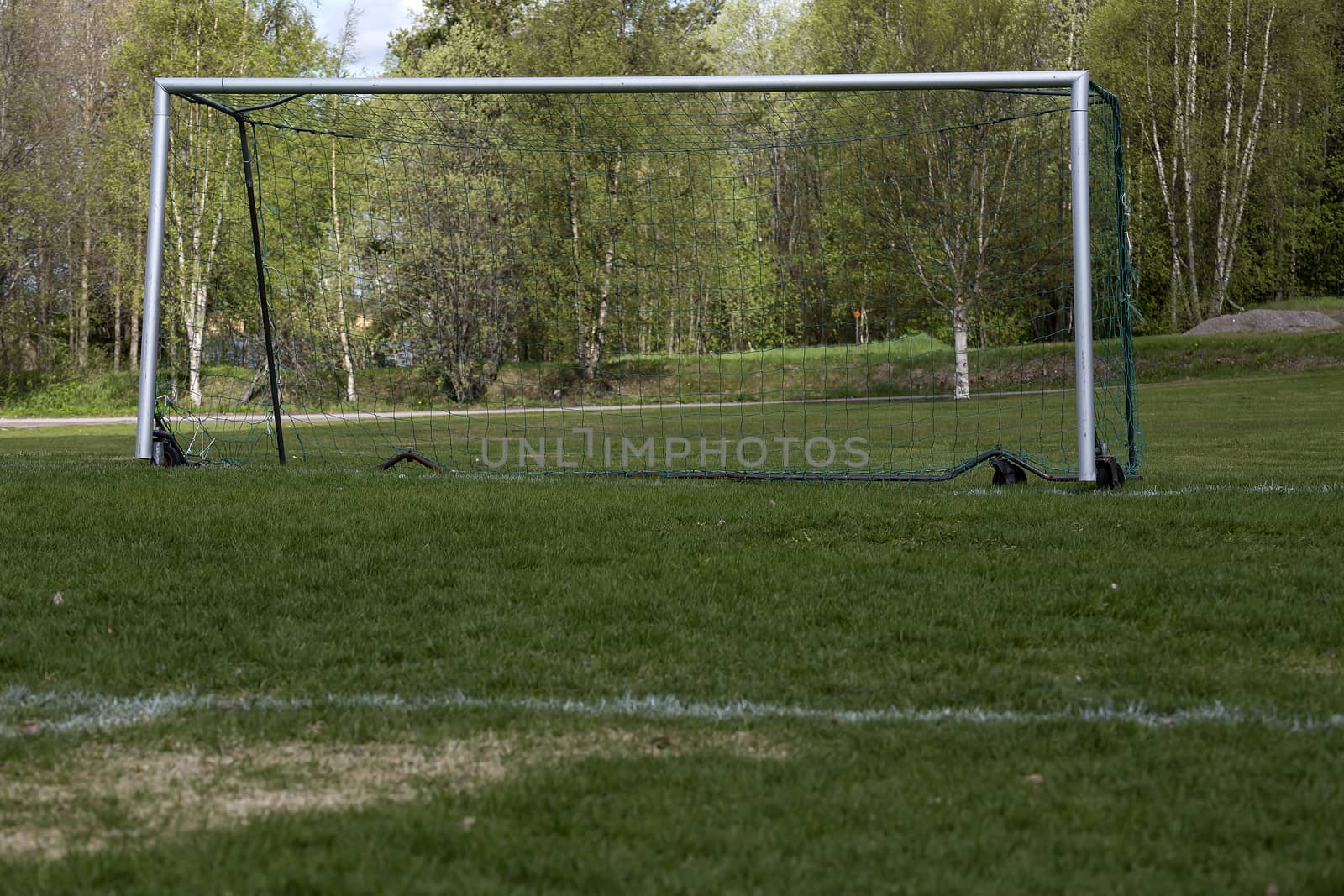 An empty soccer goal from a low perspective with some trees in the background