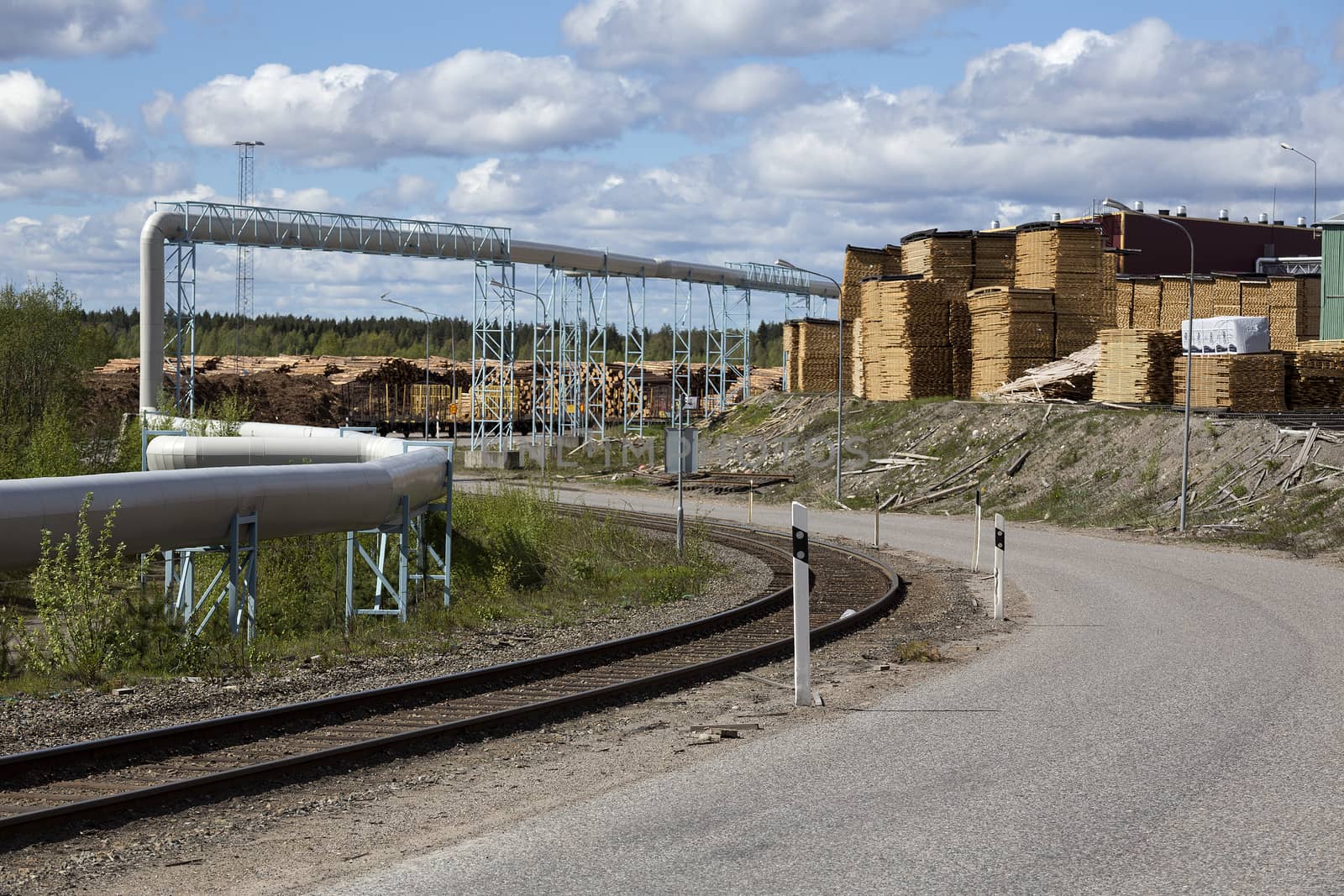 A railway and some pipes and a lot of timber on a timber producing factory