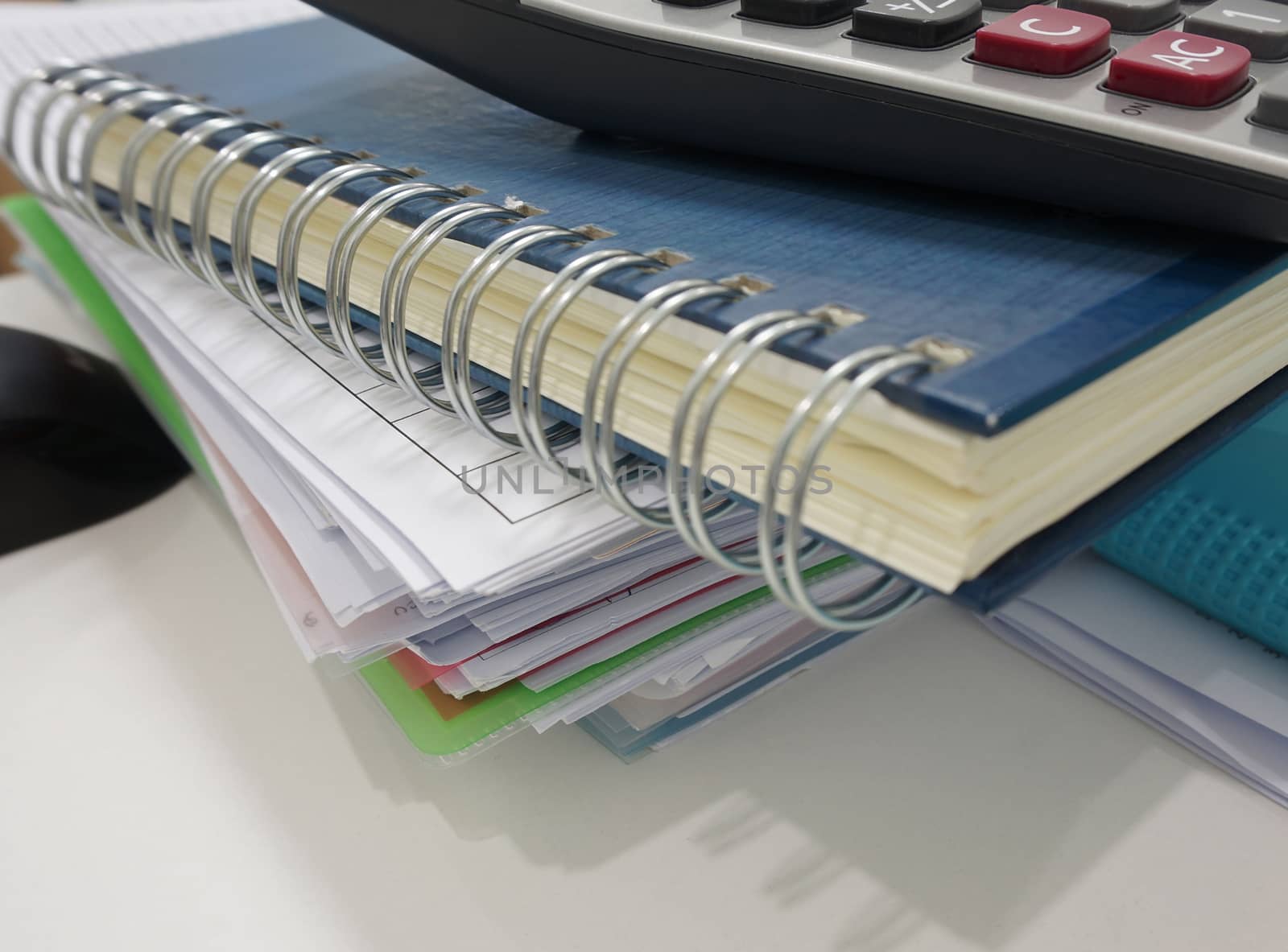 Notepad, file document and calculator placed on desk at office.
                              