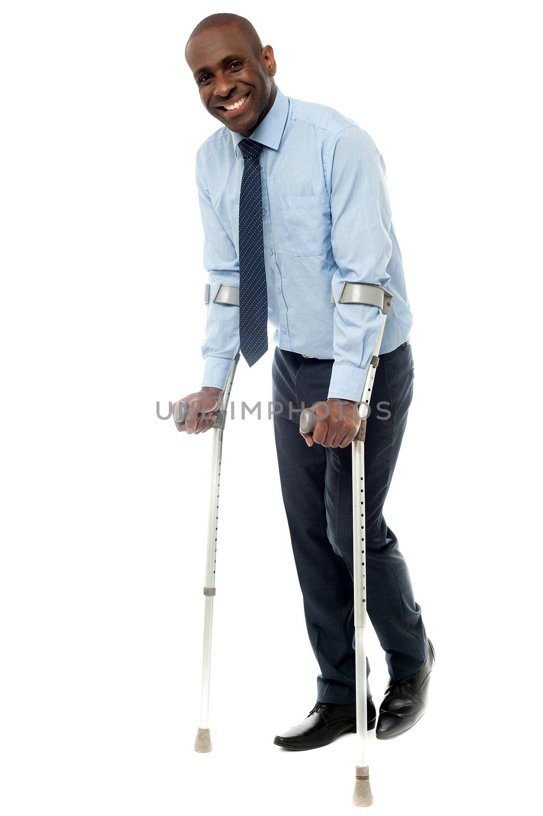 Smiling businessman trying to walk with crutches 