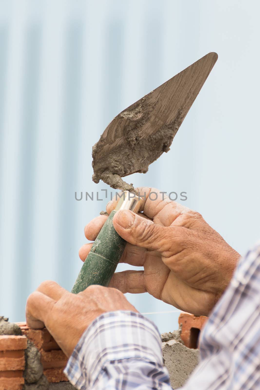 Bricklayer working in construction site of a brick wall. Bricklayer putting down another row of bricks in site