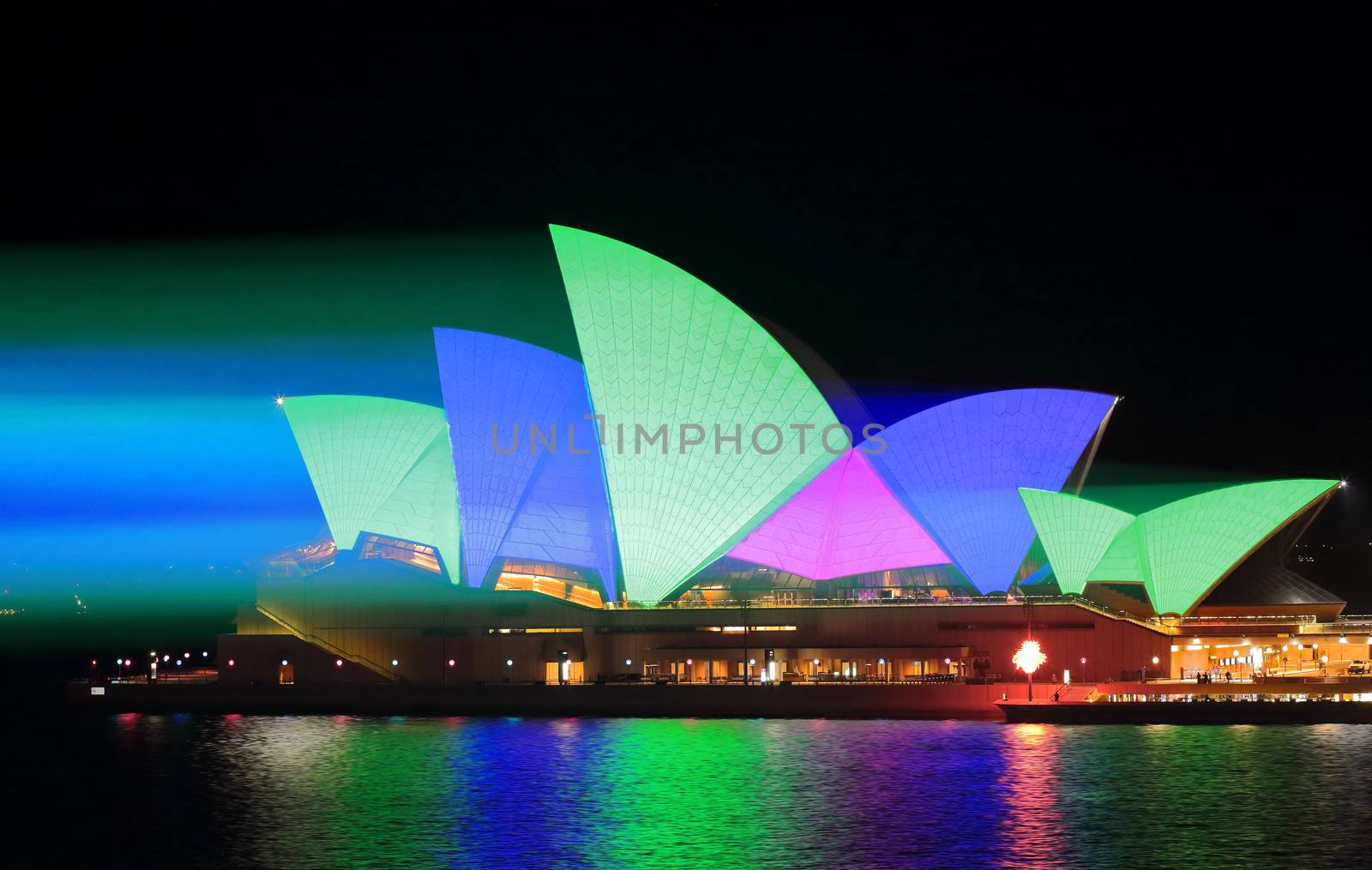 SYDNEY, AUSTRALIA - MAY 25, 2015;   Light beams stream onto the iconic landmark, the Sydney Opera House illuminating it roof sails in vivid green blue and pink during Vivid Sydney annual festival event.