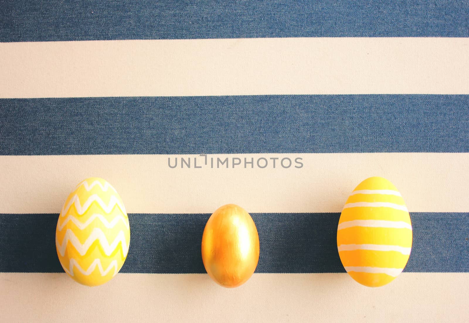 Yellow easter eggs on striped background with retro filter effect