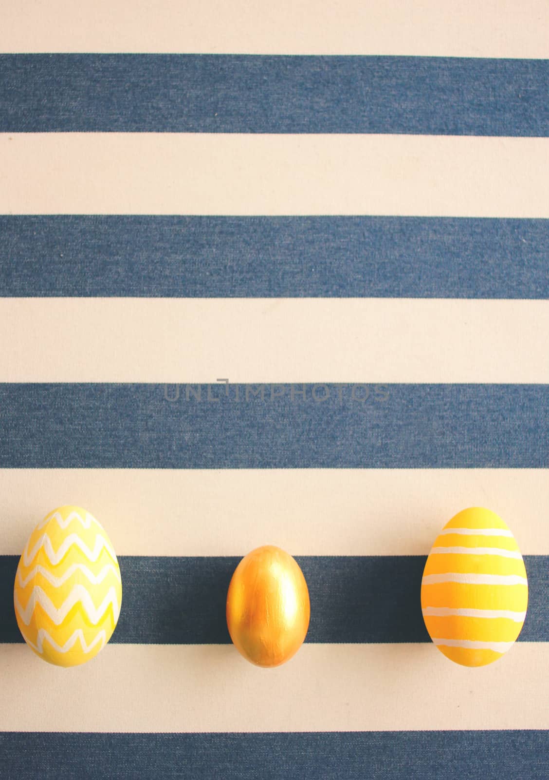 Yellow easter eggs on striped background with retro filter effec by nuchylee