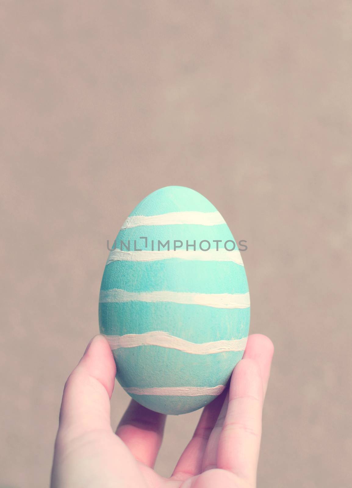 Hand holding painted easter egg with retro filter effect by nuchylee