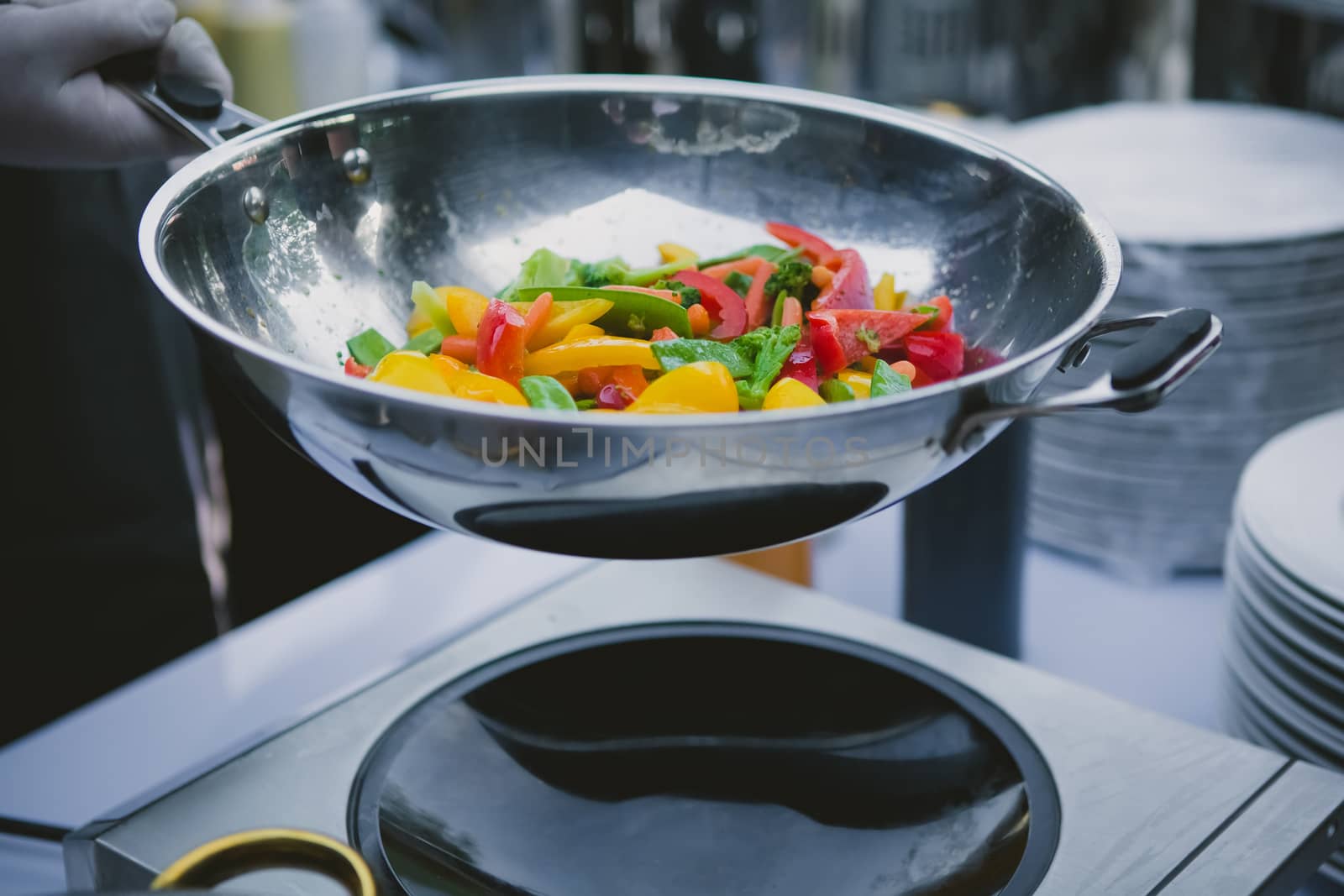 cooking vegetables in wok pan by sarymsakov