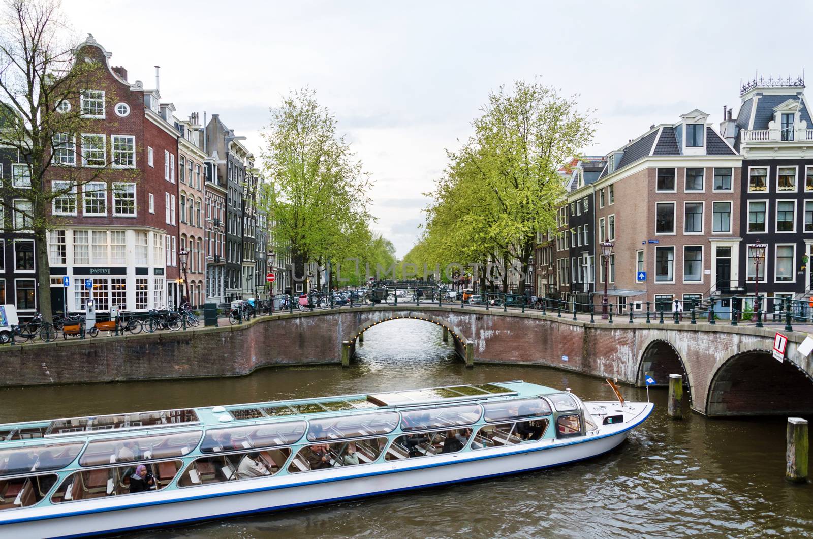 Amsterdam, Netherlands - May 7, 2015: Passenger boats on canal tour in the city of Amsterdam on May 7, 2015. Amsterdam is the capital and most populous city of the Netherlands.