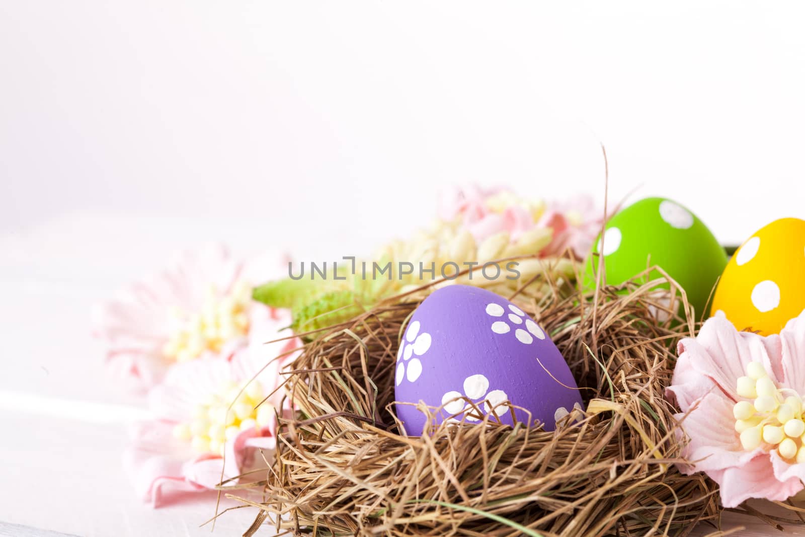 Colorful easter eggs with white points in straw nest