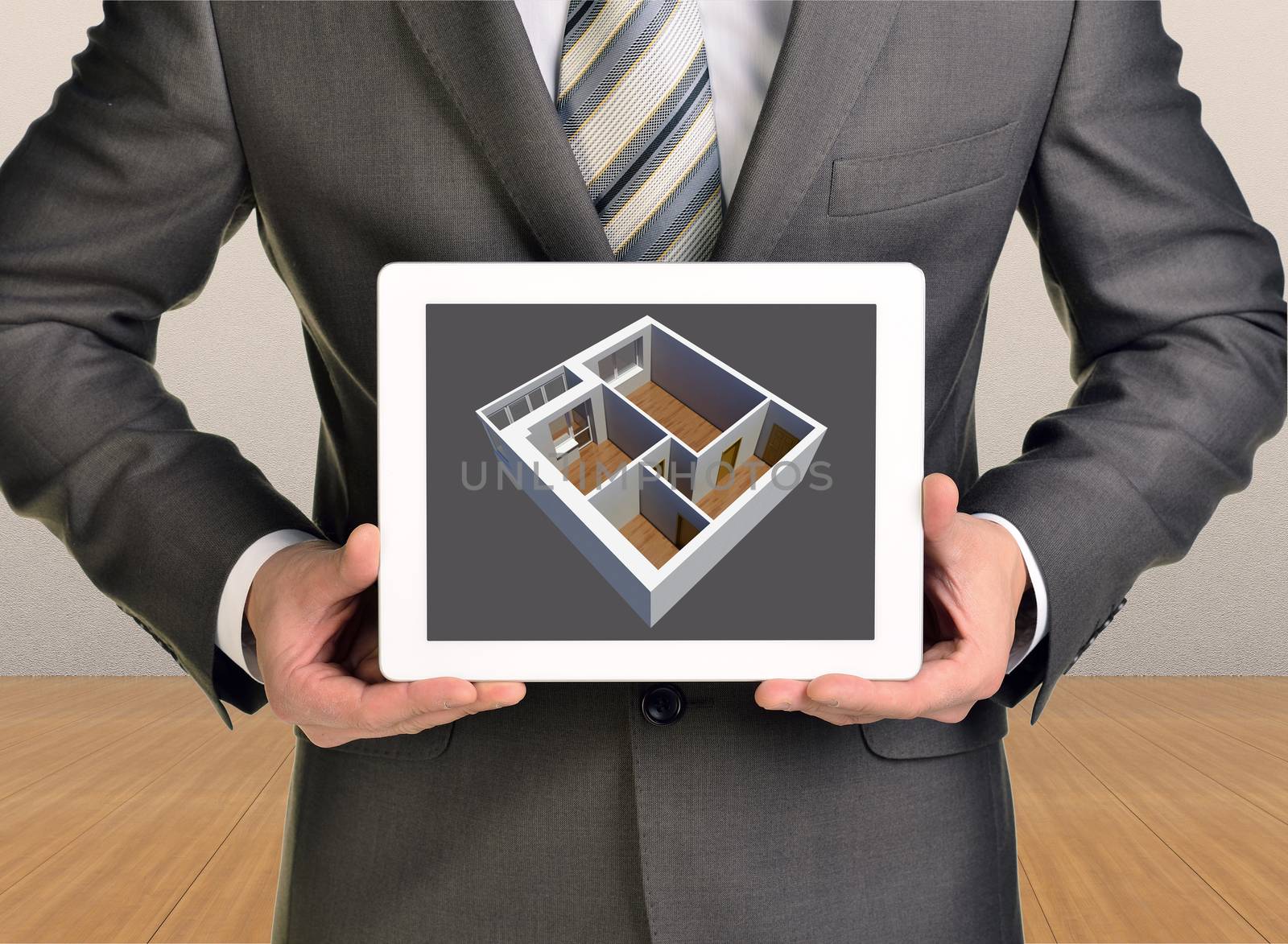 Three-dimensional model of house in tablet screen. Man holding tablet. Wooden floor and gray wall in background