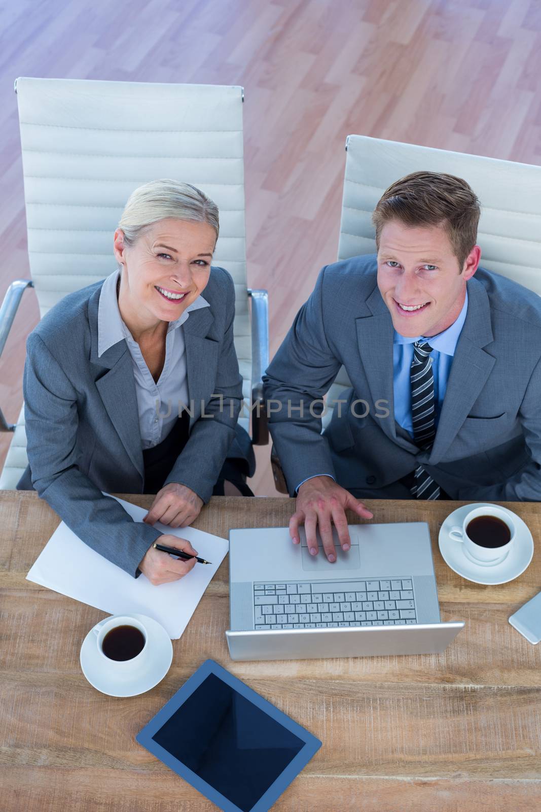 Smiling business people using laptop in the office