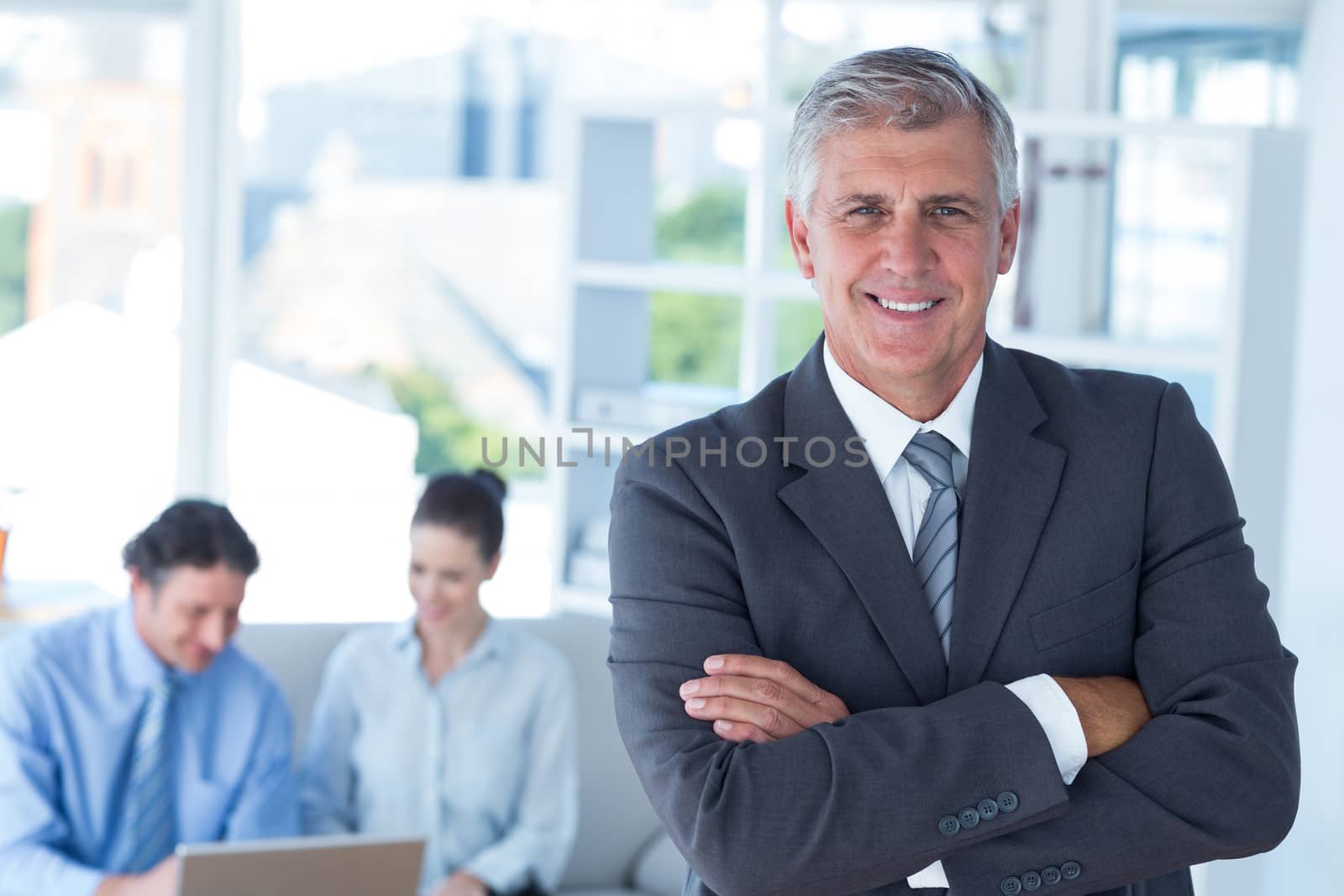 Smiling businessman with arms crossed at office