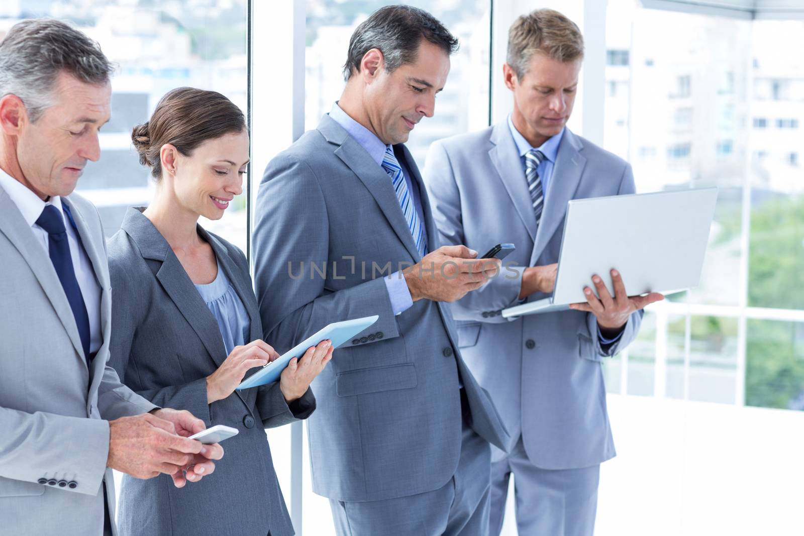 Business colleagues using their multimedia devices in the office