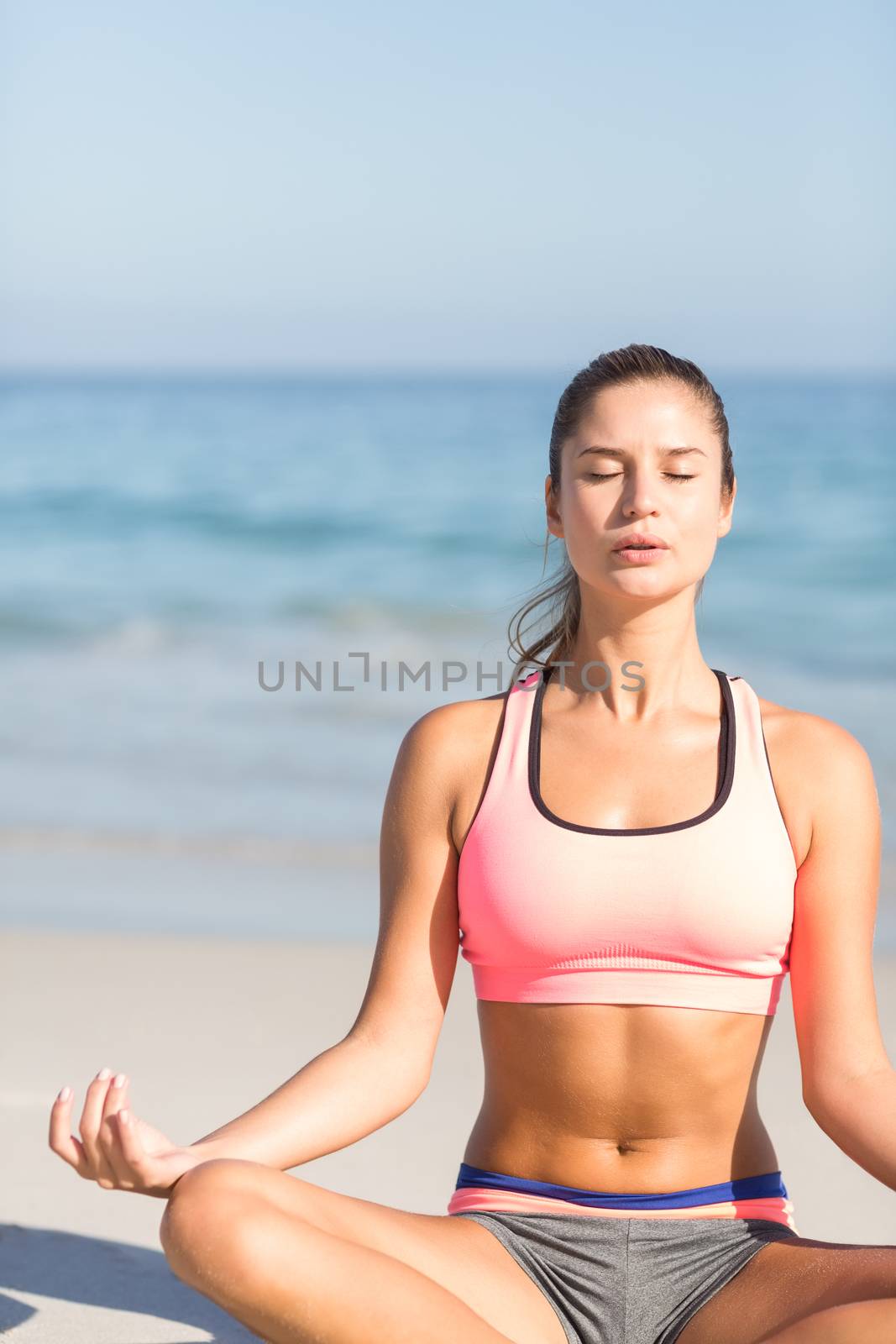 Fit woman doing yoga beside the sea at the beach 