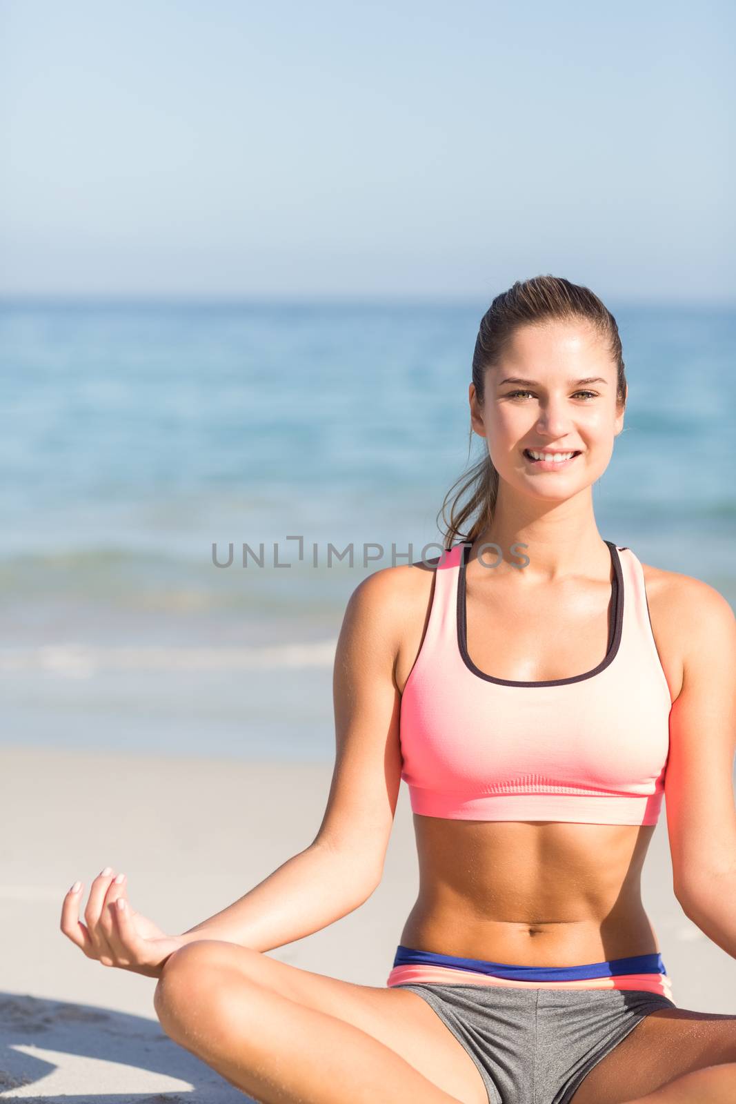 Fit woman doing yoga beside the sea at the beach 