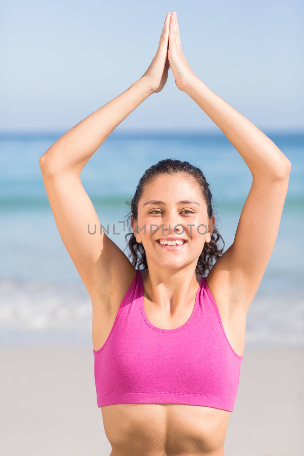 Fit woman doing yoga beside the sea at the beach 