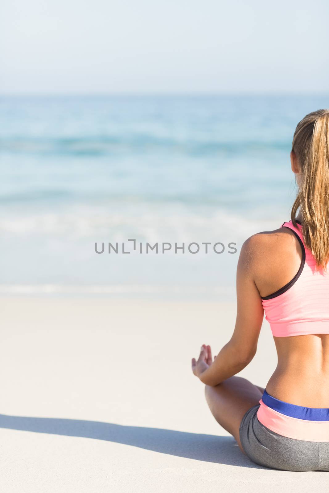 Fit woman doing yoga beside the sea at the beach 