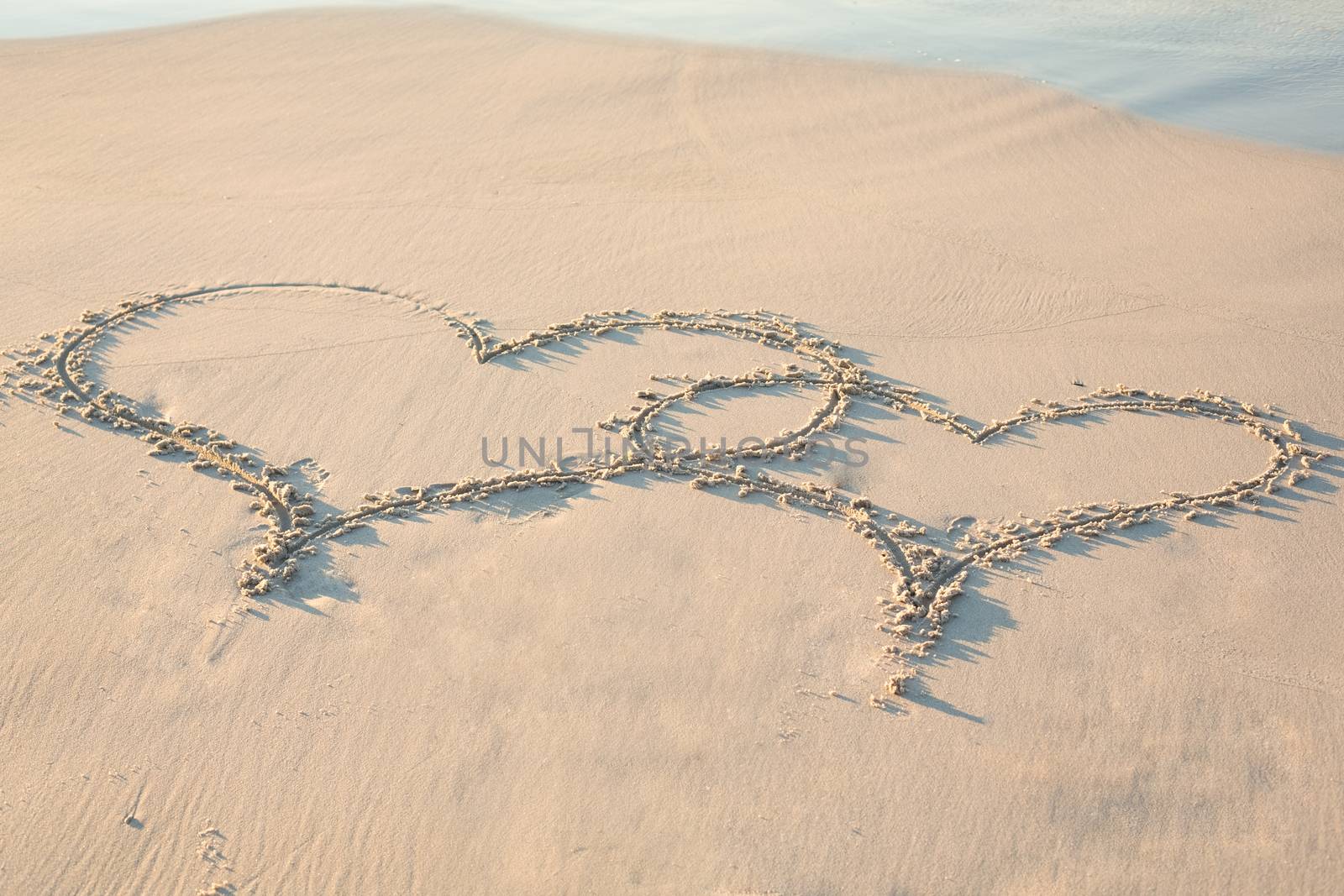 two hearts drawn in the sand  by Wavebreakmedia