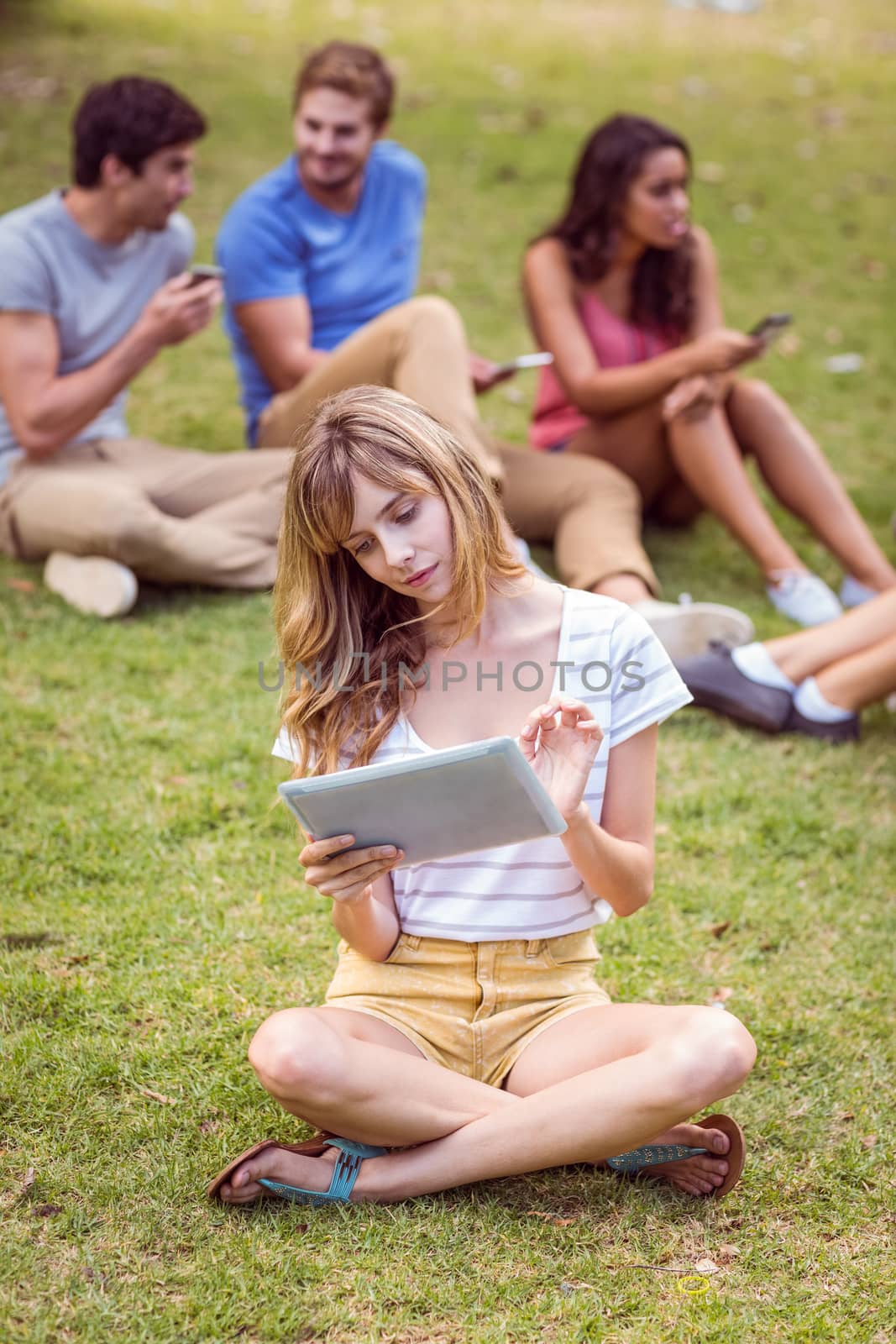 Pretty blonde using tablet in the park by Wavebreakmedia