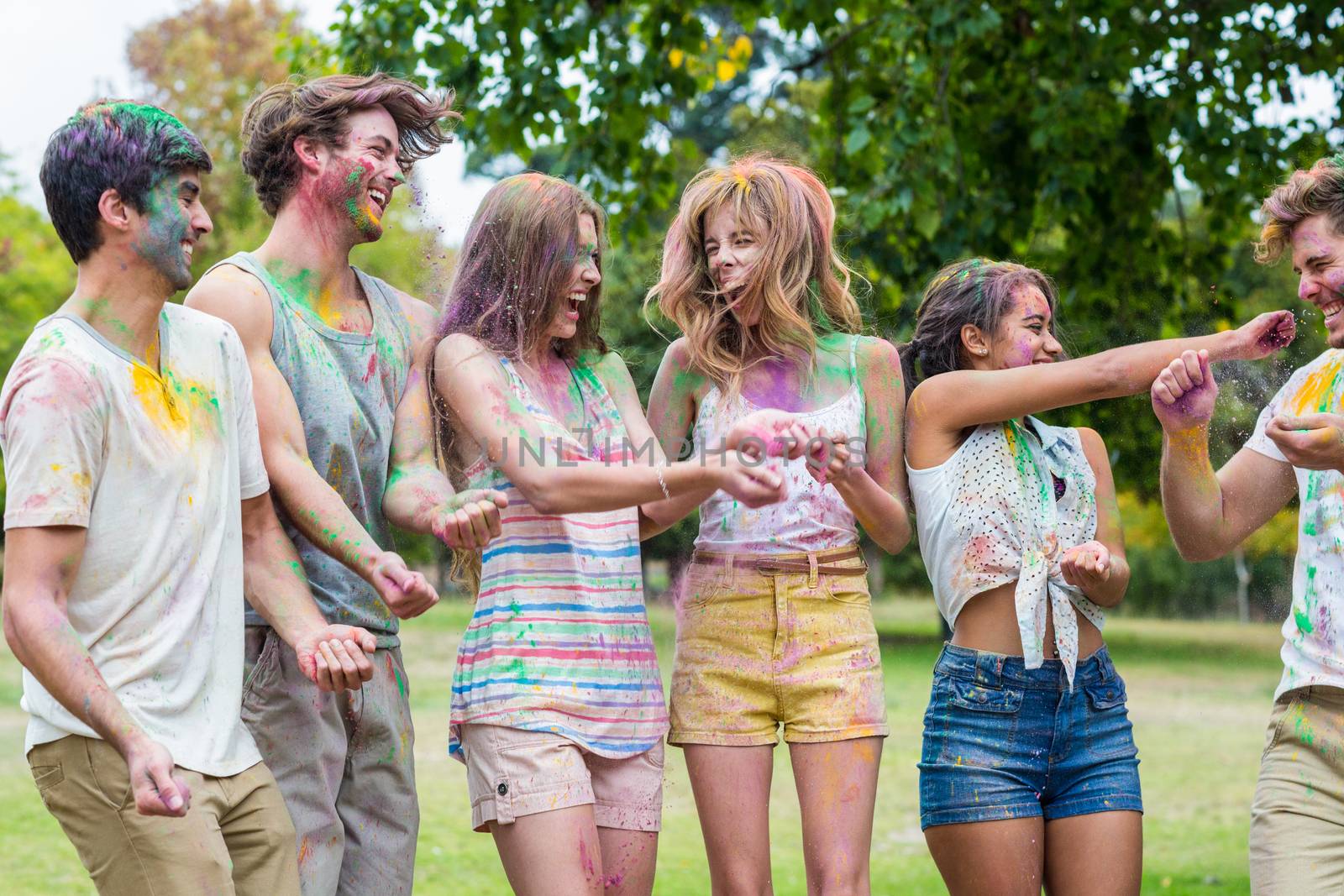 Happy friends throwing powder paint on a summer day 