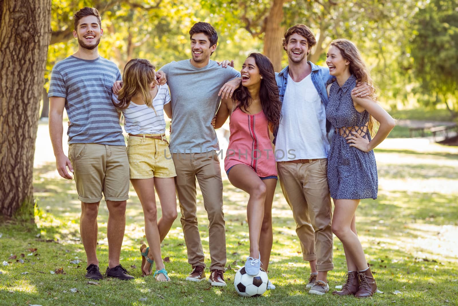 Happy friends in the park with football on a sunny day