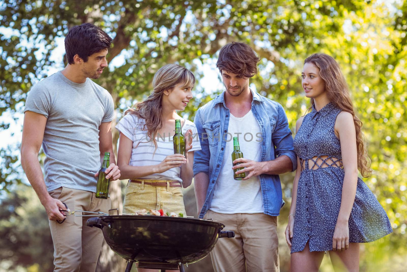 Happy friends in the park having barbecue on a sunny day