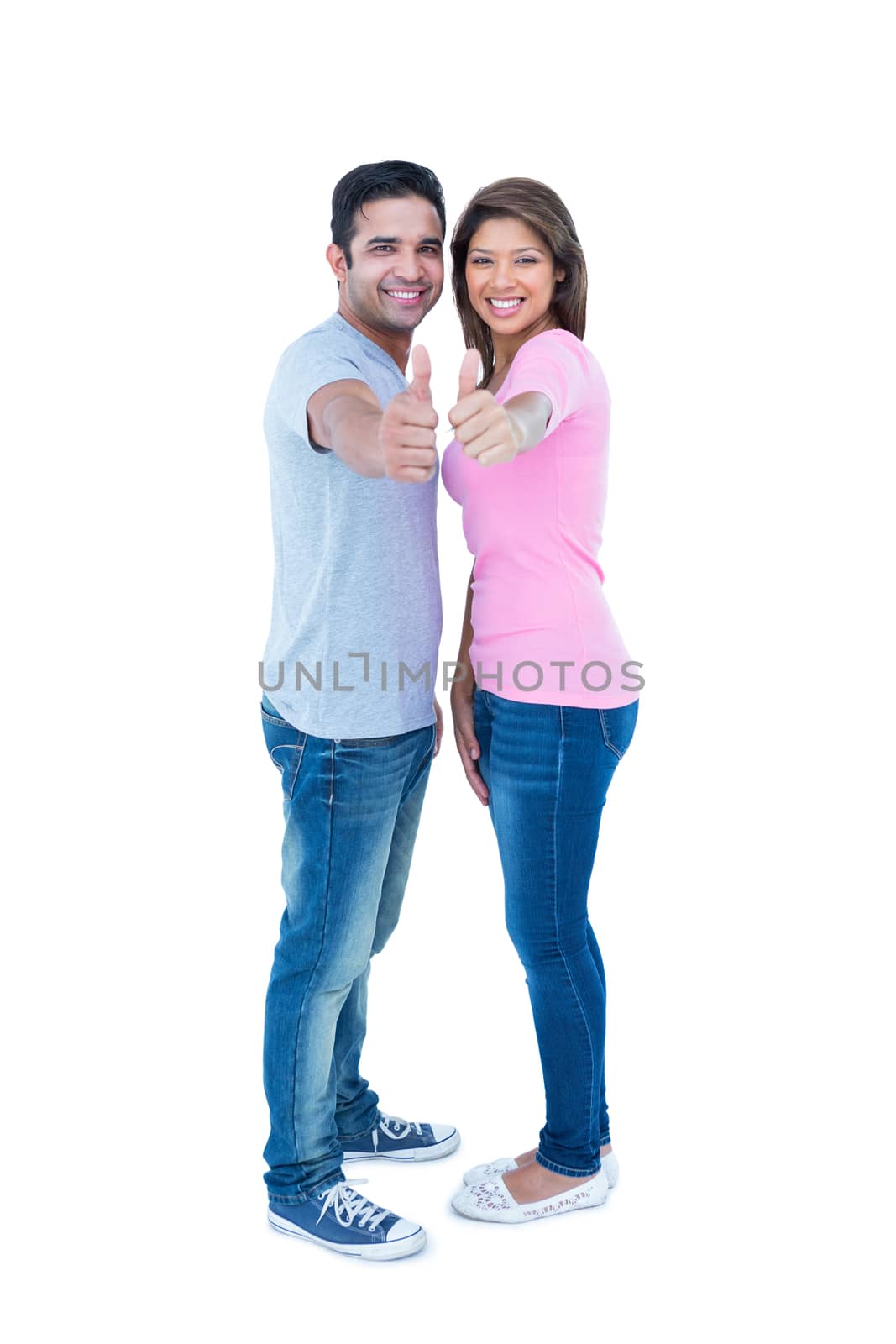 Happy couple gesturing thumbs up and looking at camera on white background