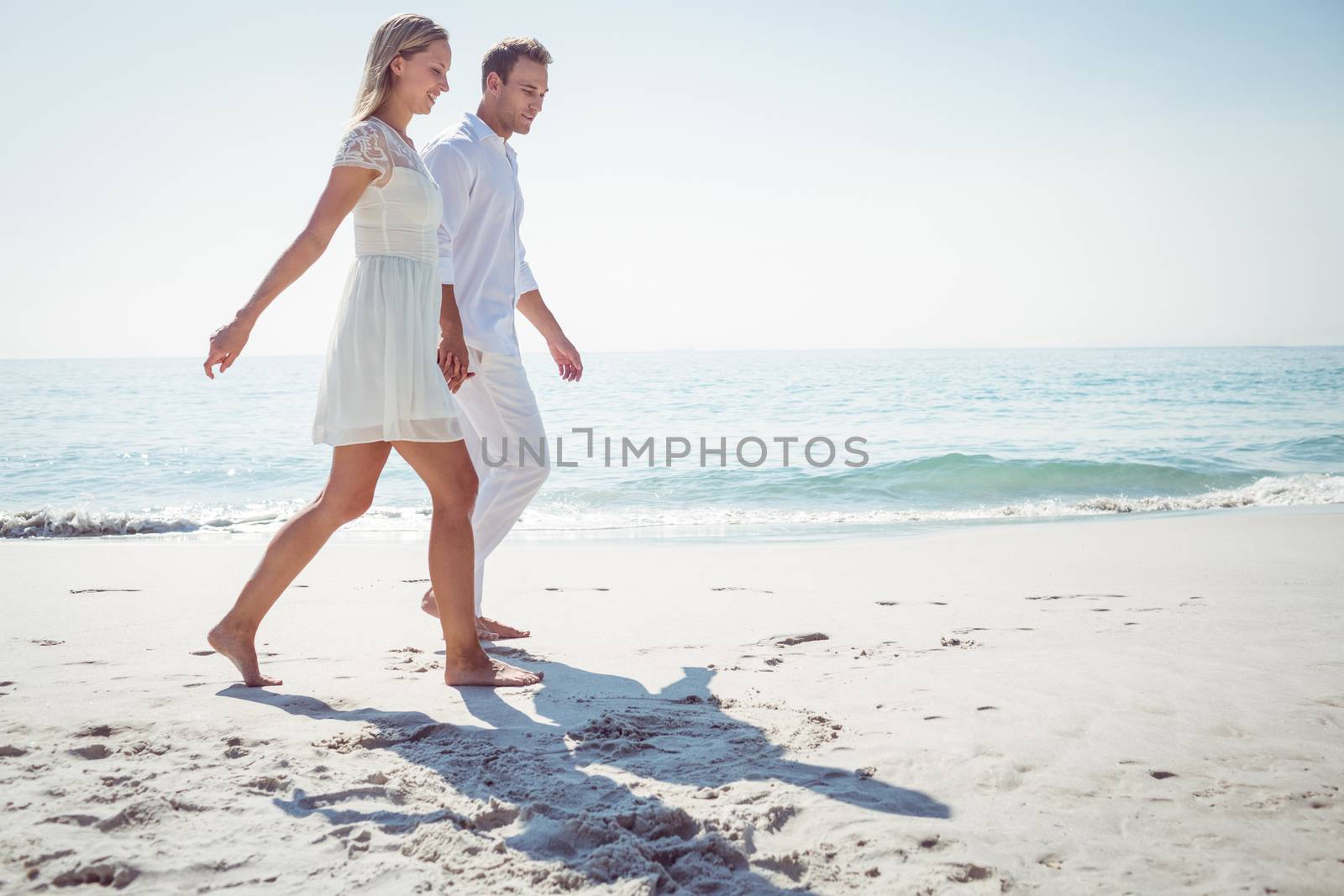 Romantic casual young couple holding hands and standing at the beach