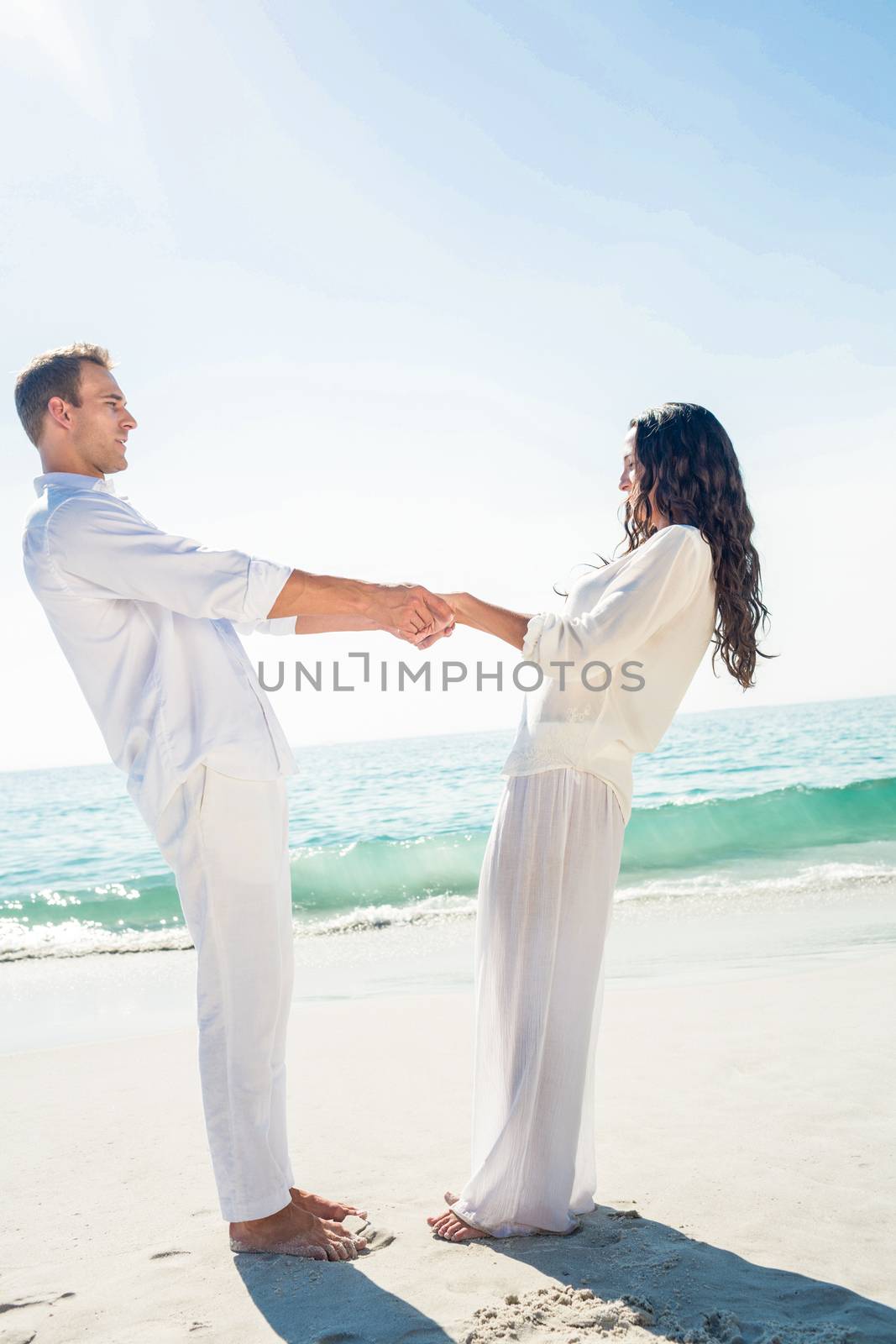 Couple holding hands and standing at beach by Wavebreakmedia