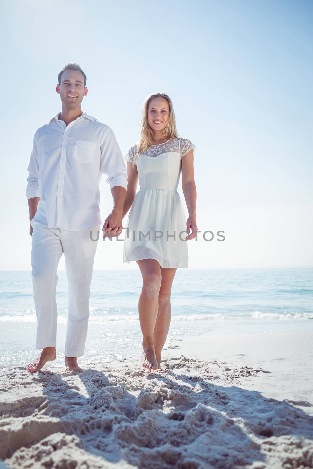 Romantic casual young couple holding hands and standing at the beach