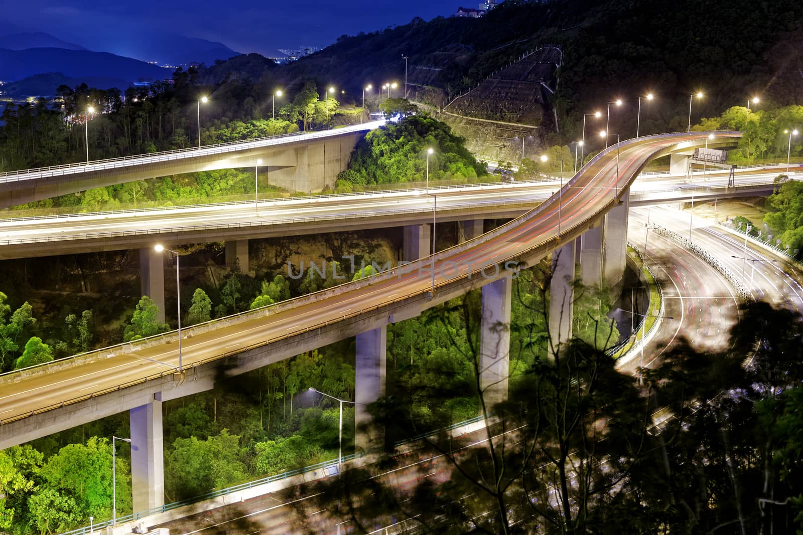 moving car on highway bridge with light through city at night 