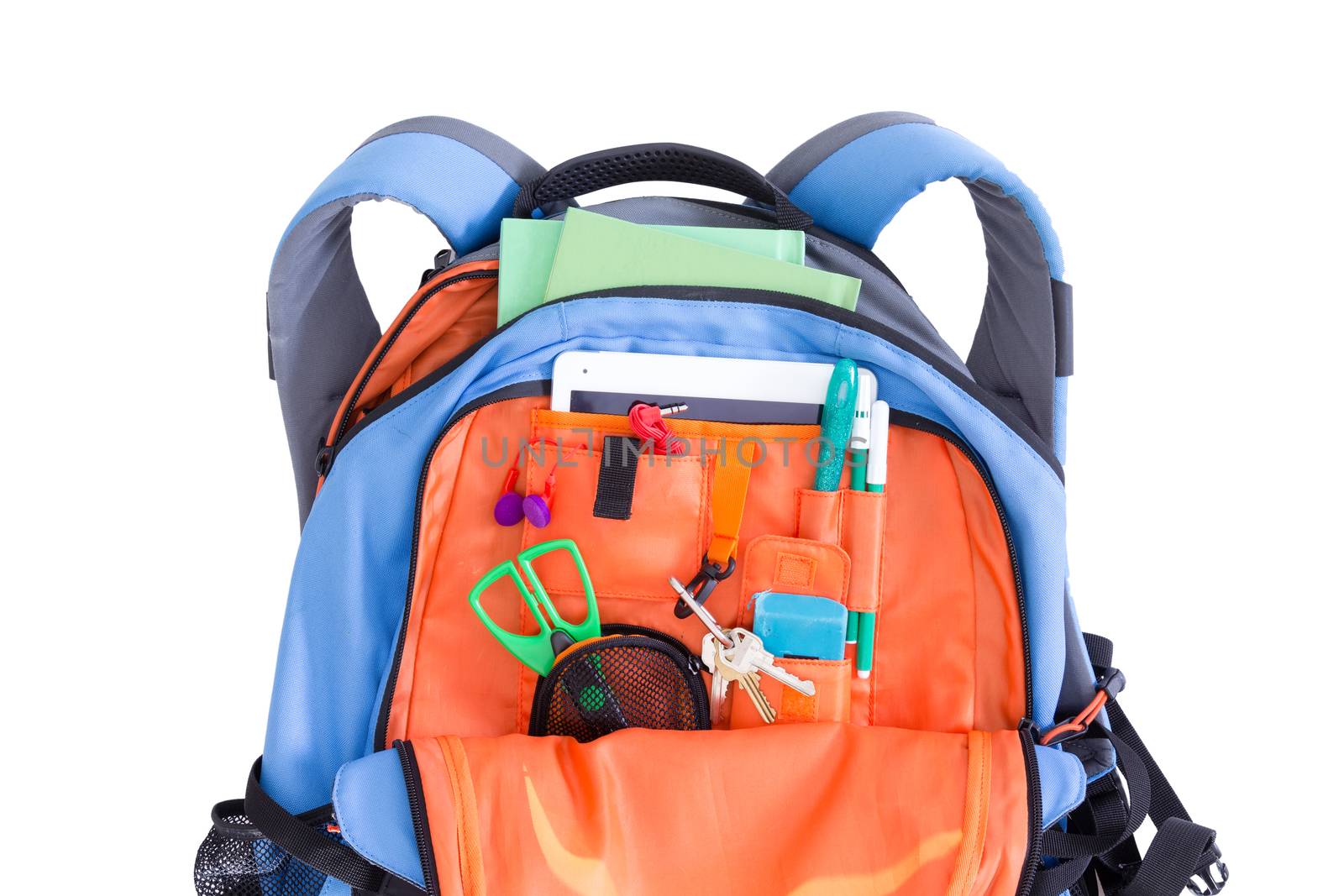 Orange and blue kids school backpack packed with a tablet, notebooks, scissors, pens, books, and stationery ready for a creative art class in an educational concept, on white