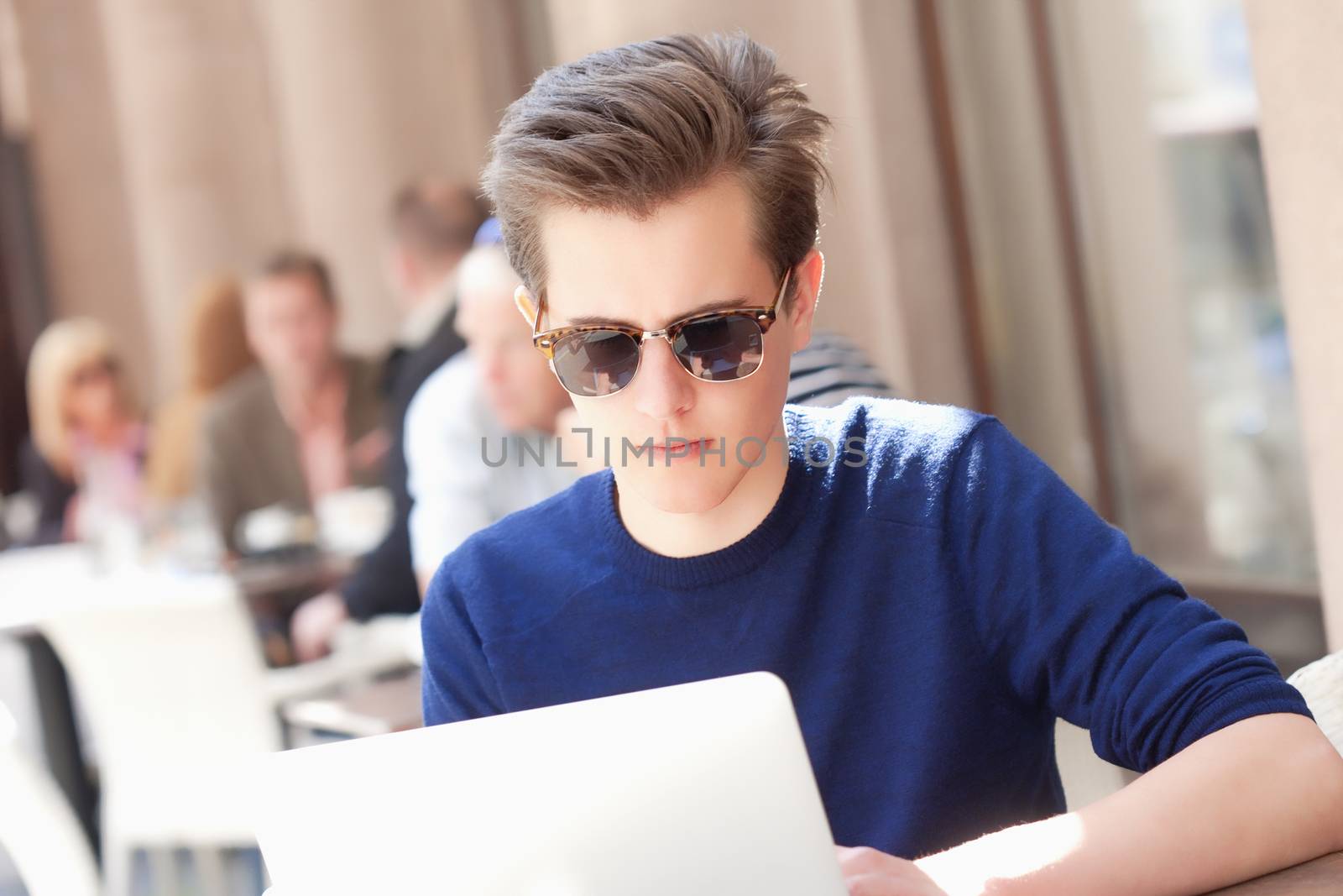 Young Man with Laptop Sitting in Outside Coffeehouse by courtyardpix