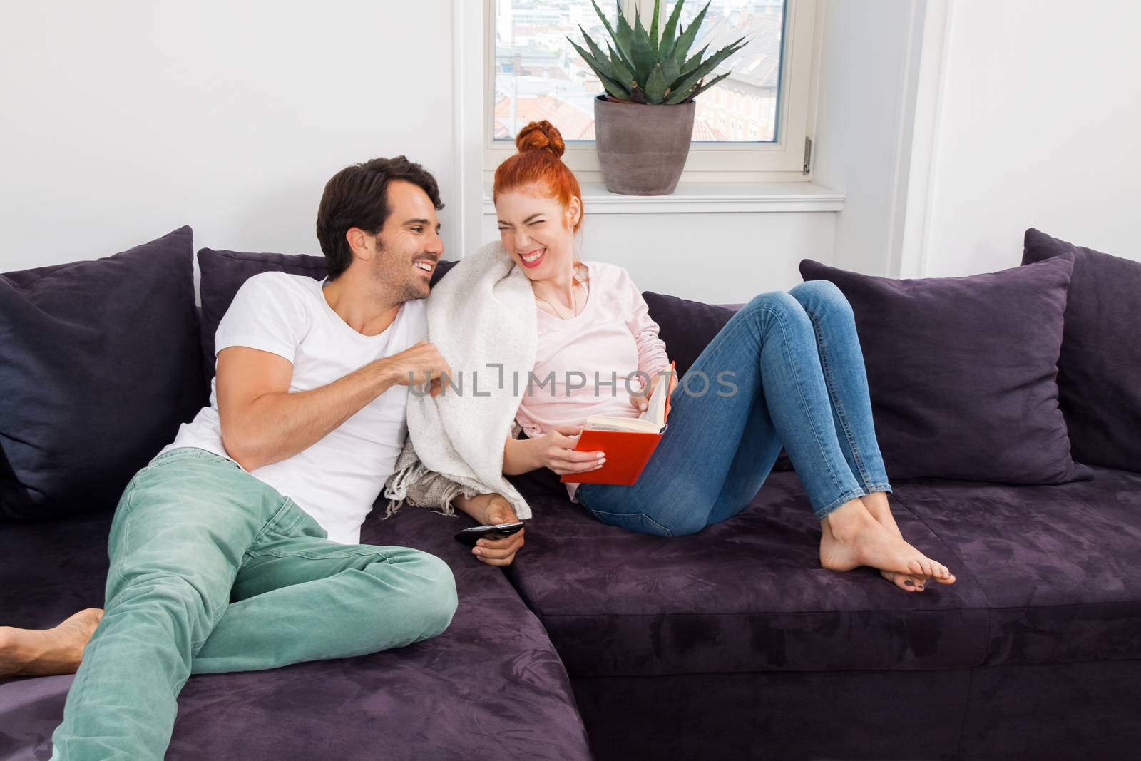 Close up Sweet Young Couple Resting at the Couch in the Living Area While Reading a Book Together Seriously.