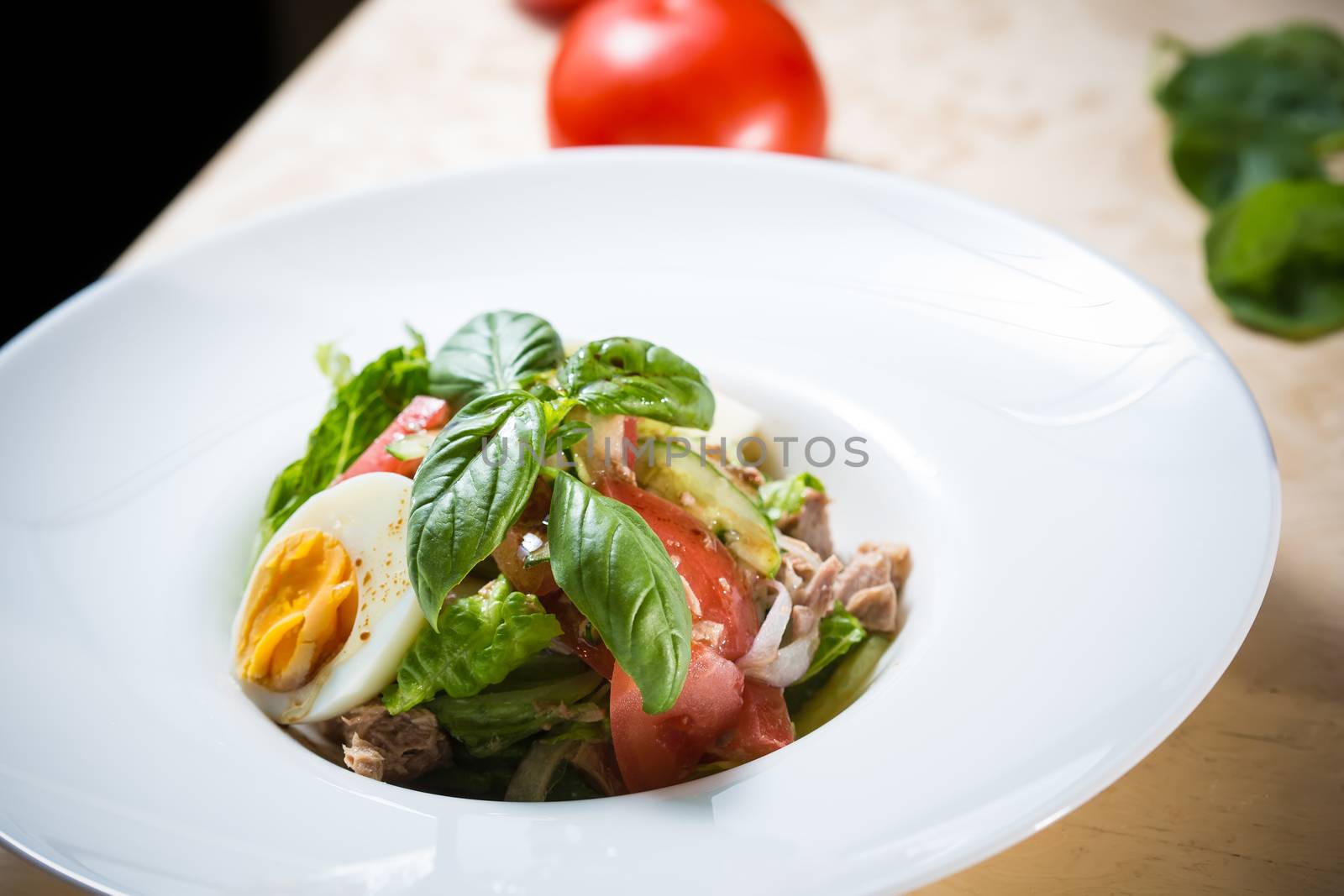 Closeup of plate of spring mix salad with strawberry, eggs and tuna