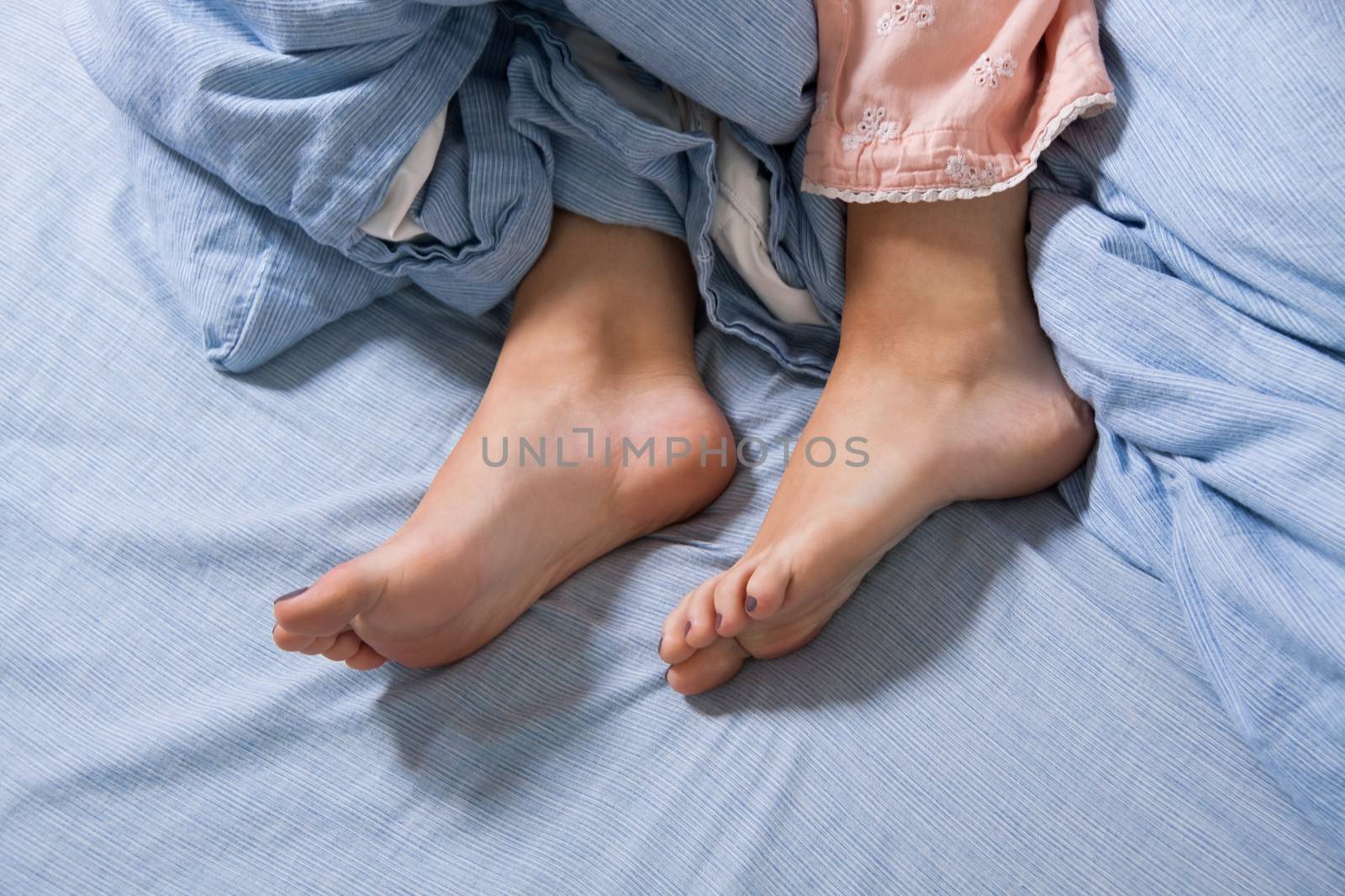 Close up Bare Feet of a Young Woman Lying Down on a Blue Bed, Captured in High Angle View.