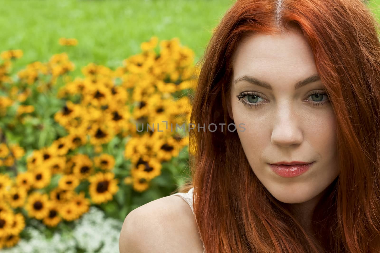 Close up Young Woman with long red Hair Relaxing at the Garden While Looking Afar