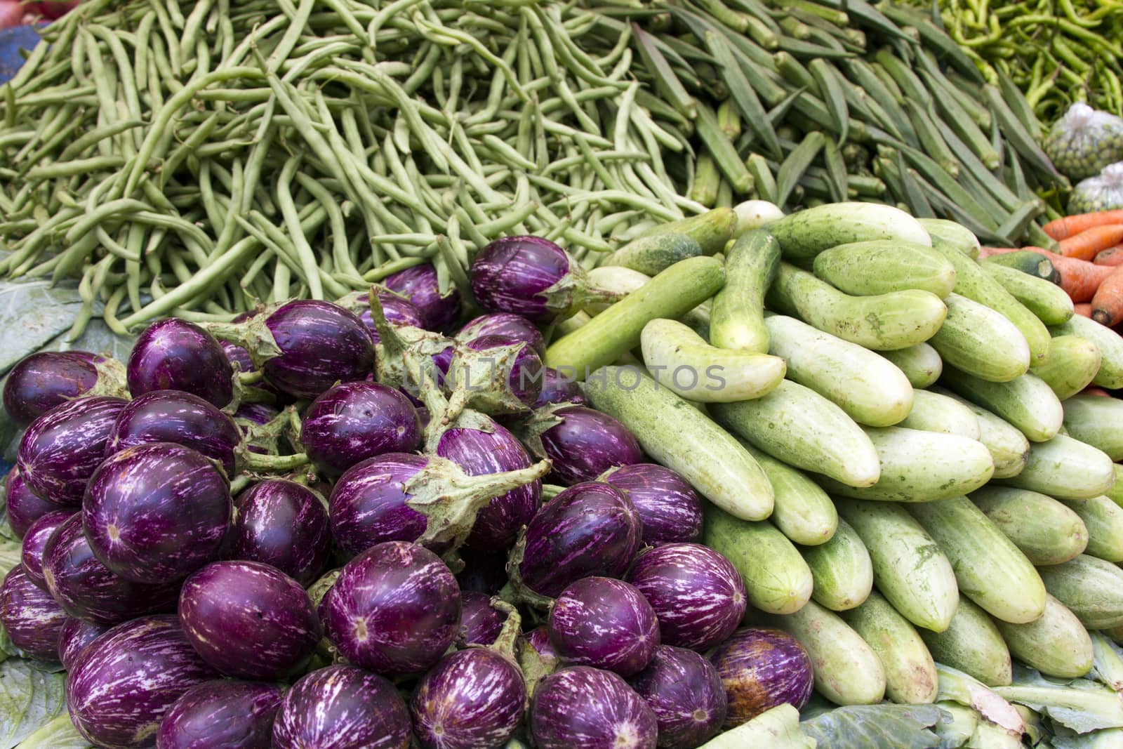 Fresh juicy vegetables, eggplant, cucumber, beans on a counter in the Indian market Goa.