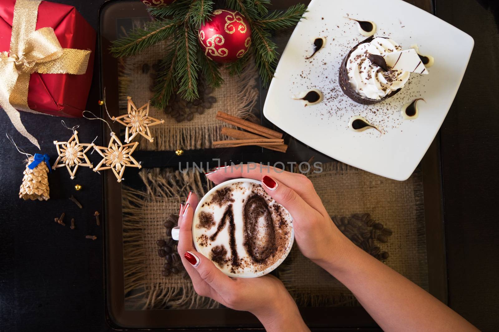 Hands holding mug of coffee with ten signs, close-up, on new year background